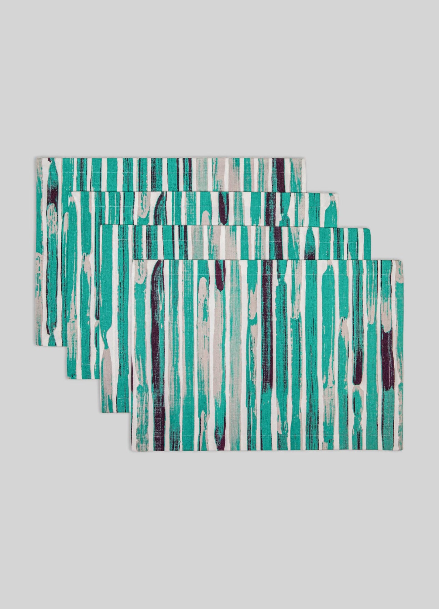 Set of four fabric placemats with abstract vertical stripe patterns in shades of turquoise, white, and dark purple on a light gray background.