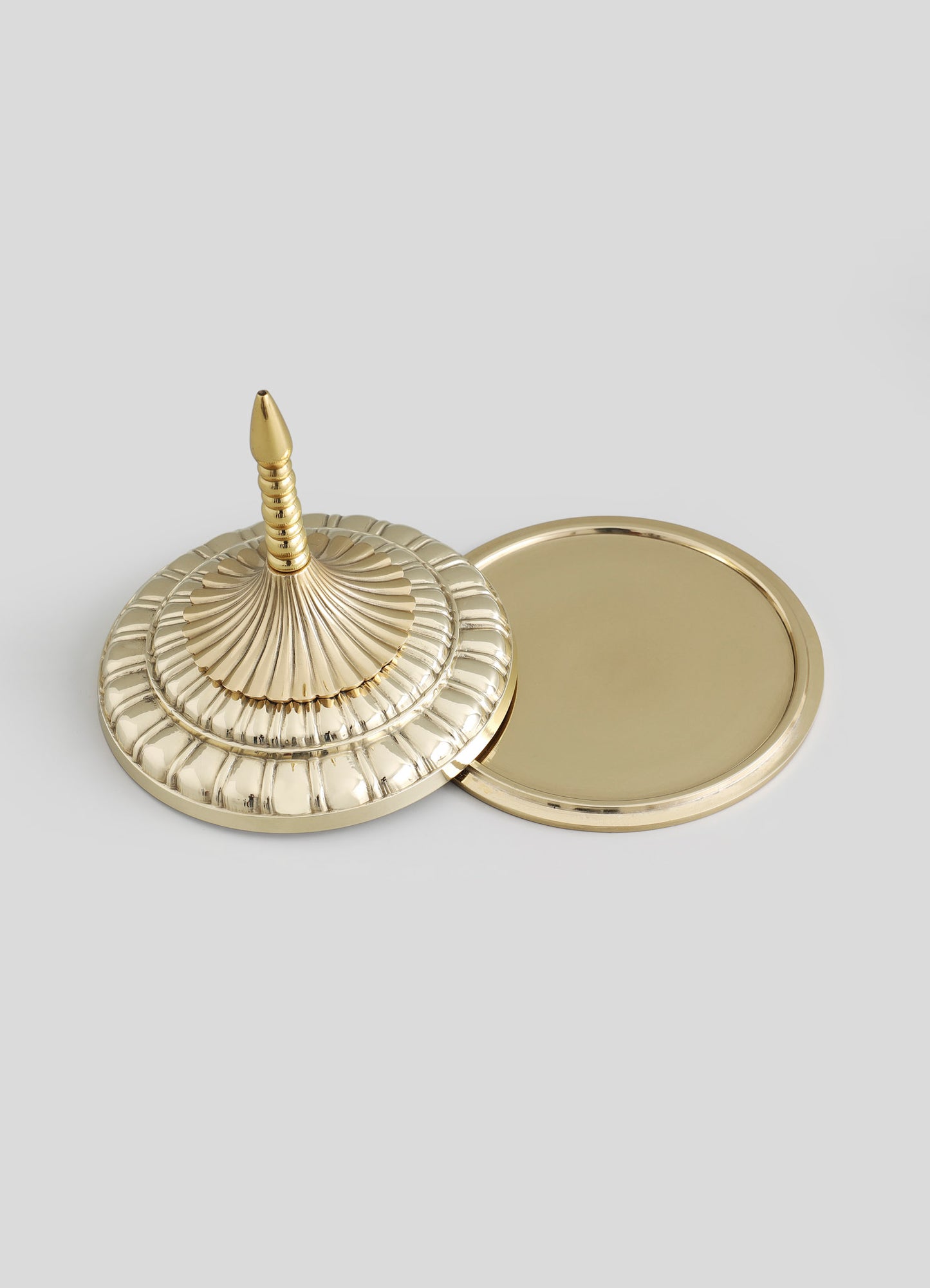 A gold-toned brass tray with a domed, spiral-patterned lid featuring a pointed finial, and a matching round mirror with a smooth border.