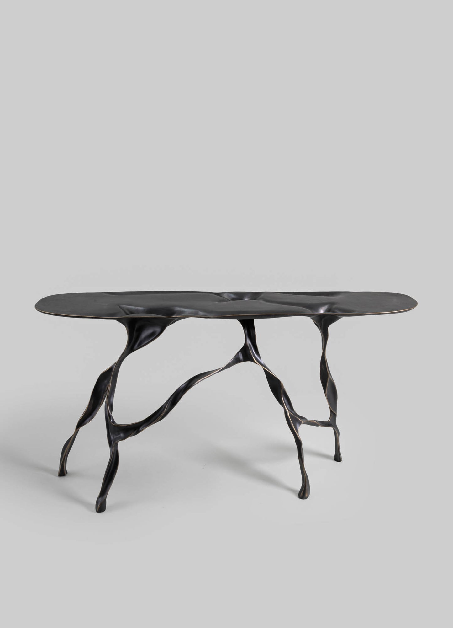 A contemporary coffee table with an irregularly shaped black top and sculptural, branch-like legs in black and gold-tone metal finish.