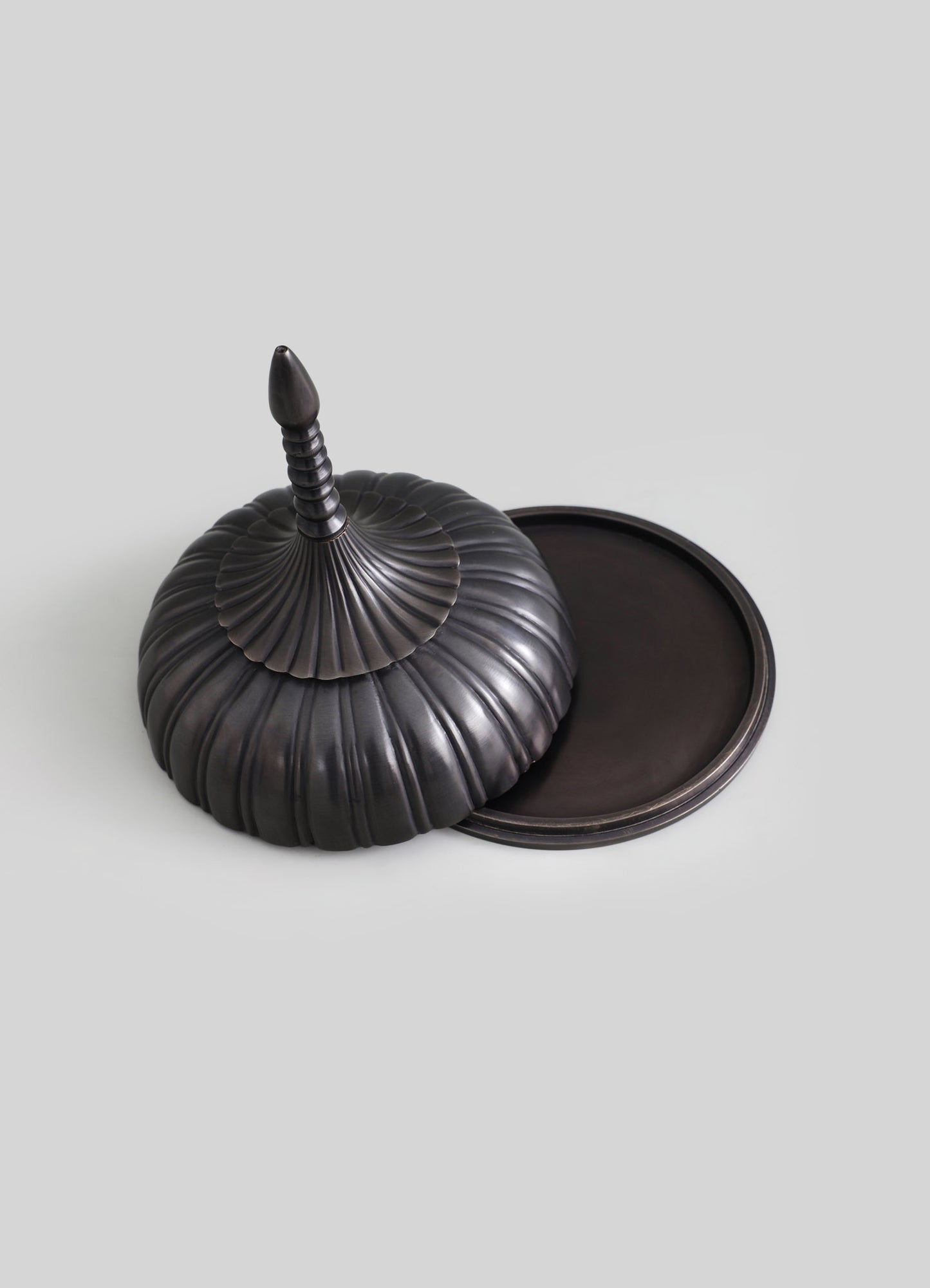 A black metal decorative container with a ribbed, pumpkin-like shape and a pointed, spiral finial on top, paired with a matching round tray. The design features a matte finish and a vintage-inspired, ornate style.