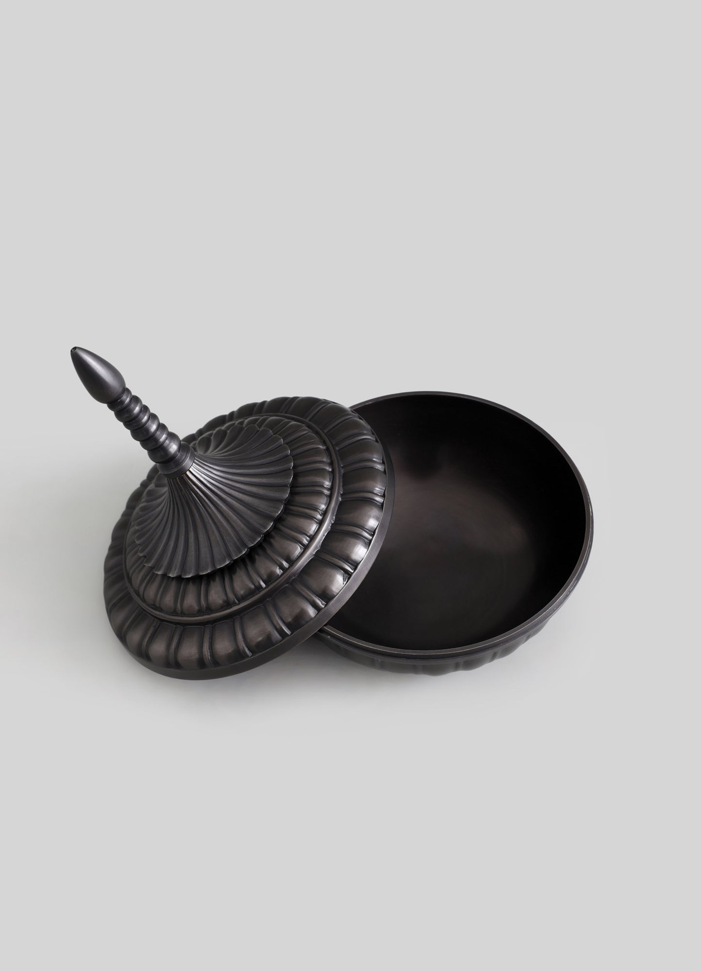 A black decorative box with a removable lid featuring a tiered, ruffled design and a turned finial handle, made from a smooth material with a matte finish.
