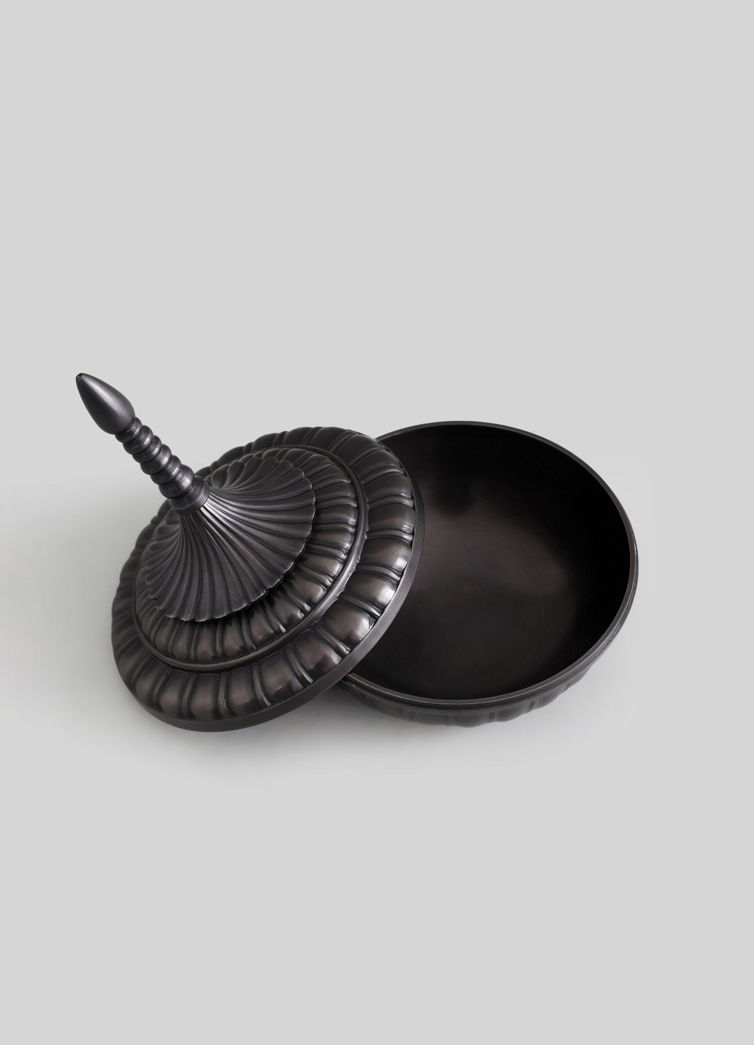 A black decorative box with a removable lid featuring a tiered, ruffled design and a turned finial handle, made from a smooth material with a matte finish.