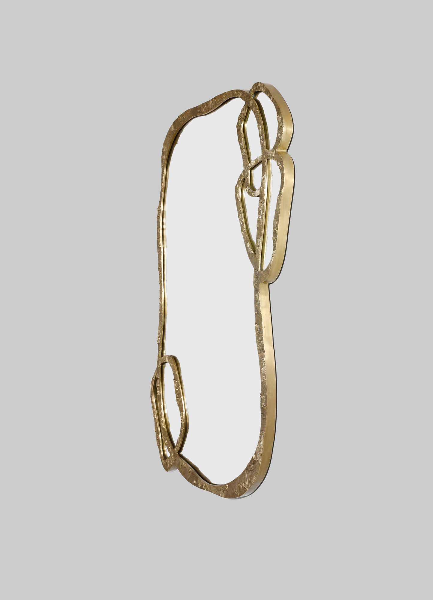 A decorative wall mirror with a gold-tone metal frame featuring an organic, irregular shape and textured surface, set against a plain background.