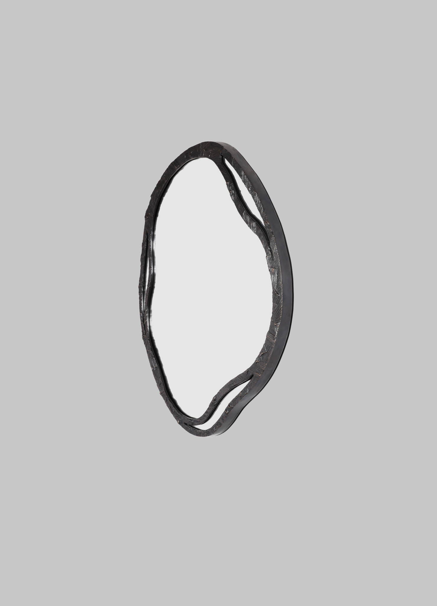 A decorative mirror with a textured black metal frame featuring organic, wavy lines, set against a light grey background.