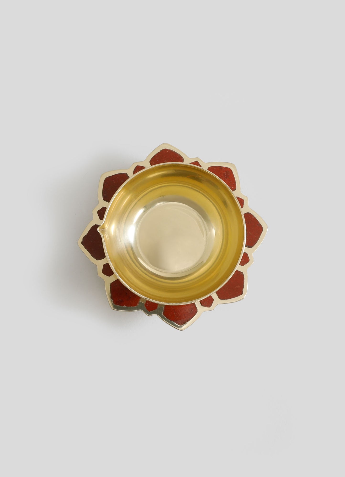 A glass bowl with a golden yellow tint placed on a decorative coaster with a floral motif in warm red tones. The bowl has a smooth, rounded shape with a shiny surface.