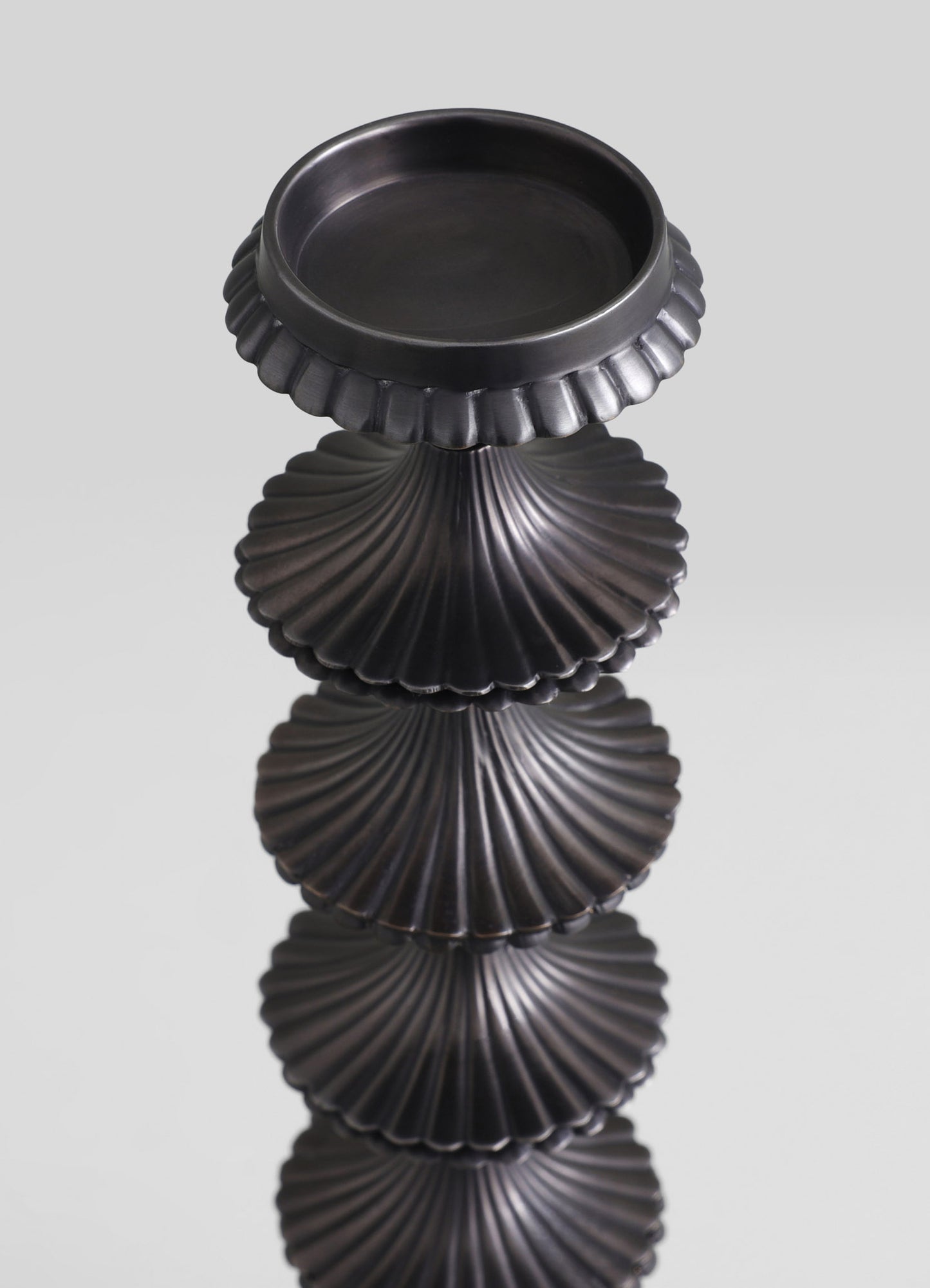Black ceramic or resin side table with a scalloped, shell-like base and a smooth, round top, exhibiting a contemporary and elegant style.
