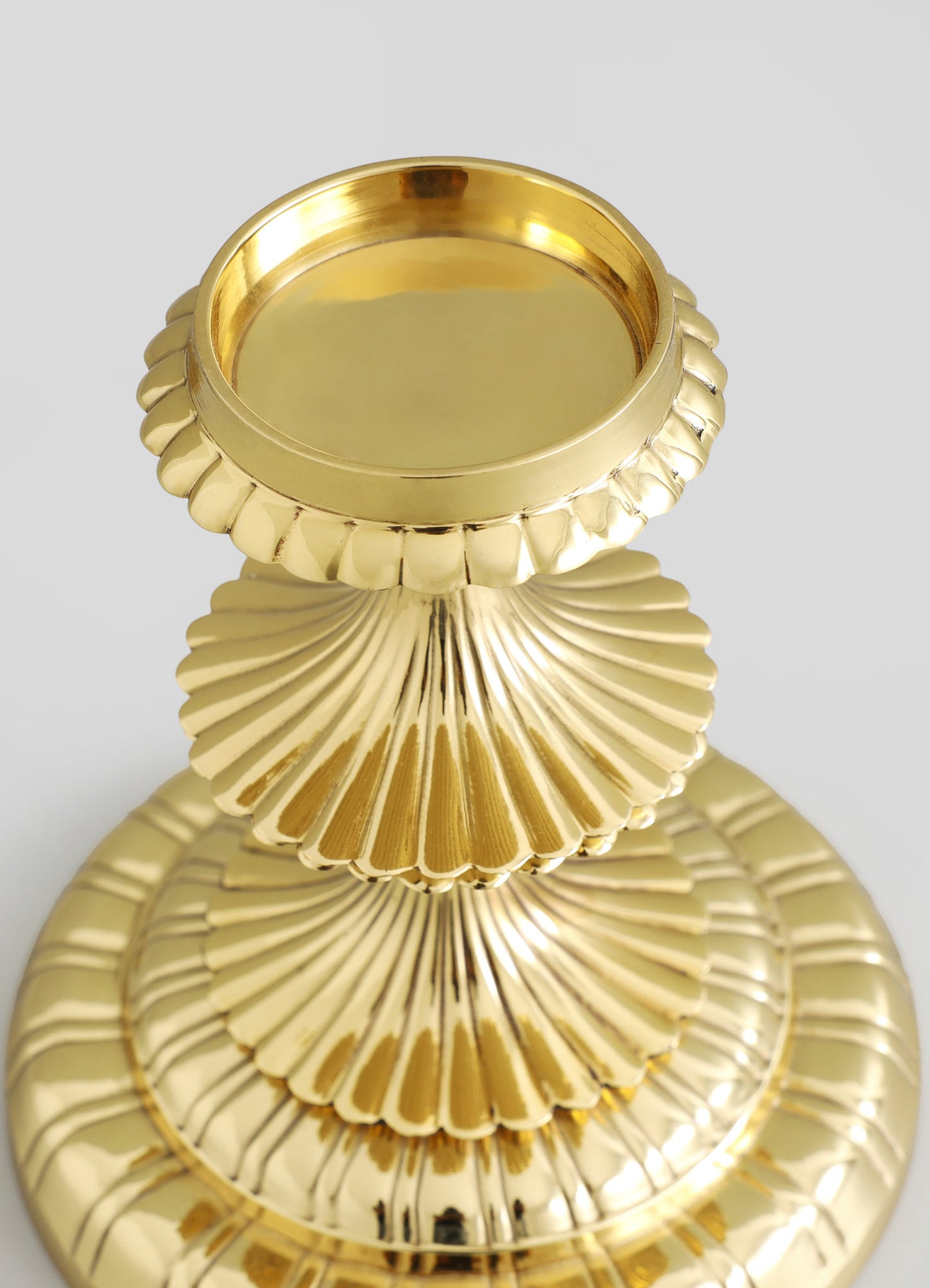 A set of three stacked decorative trays with scalloped edges and a shiny gold finish, made of metal. The trays feature a radial pattern on the edges, creating a visually striking, luxurious look.