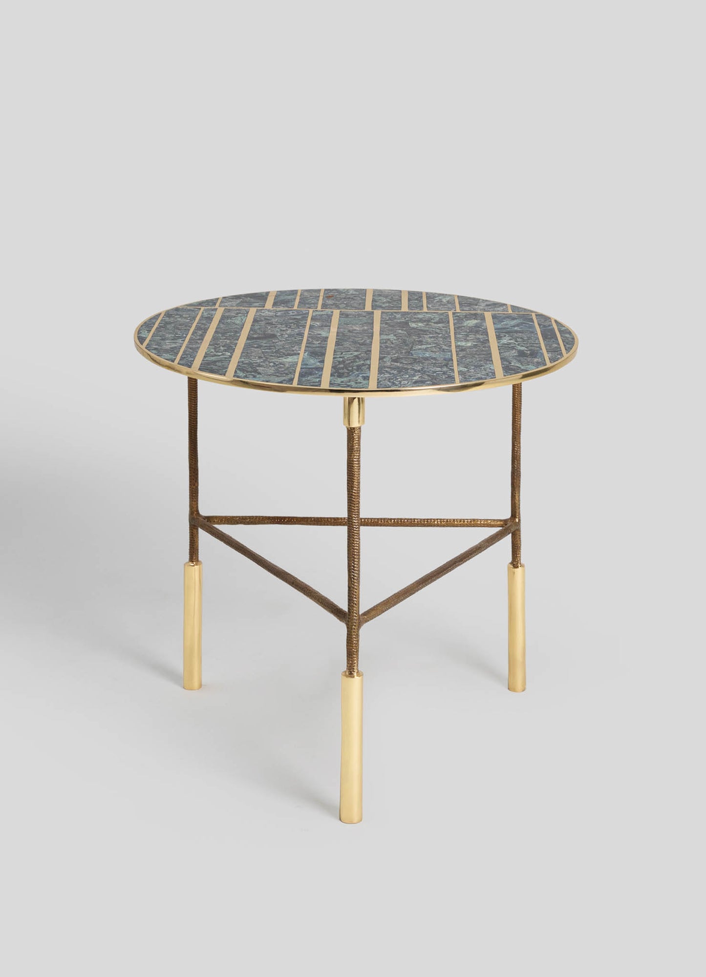 A round side table with a marble top featuring a dark gray and green pattern, edged with a brass trim. The table has a metal frame with a bronze finish and four contrasting gold-colored legs.
