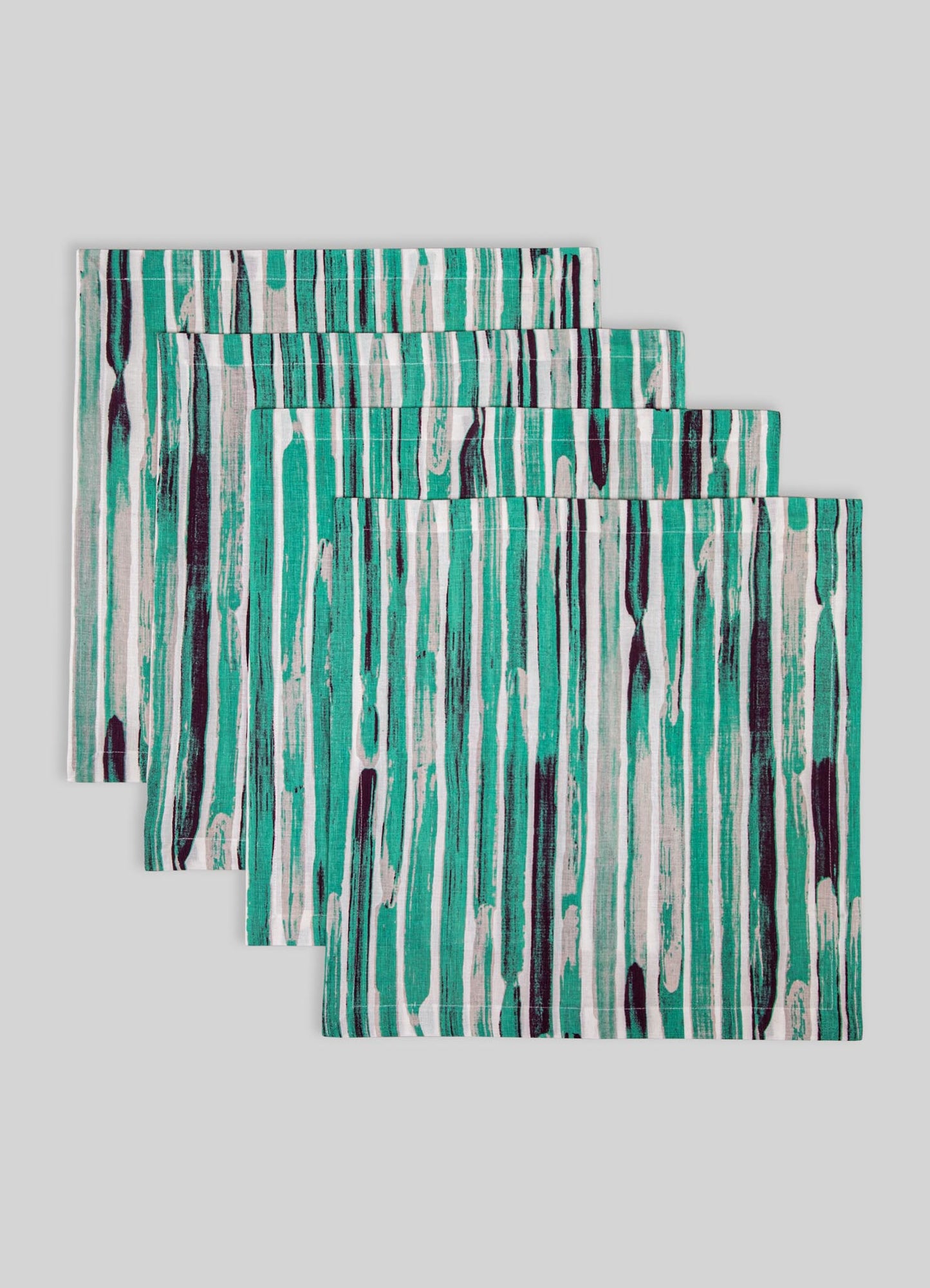 Set of three fabric placemats featuring an abstract vertical stripe pattern in shades of teal, black, and white, made from a smooth material with cleanly finished edges.