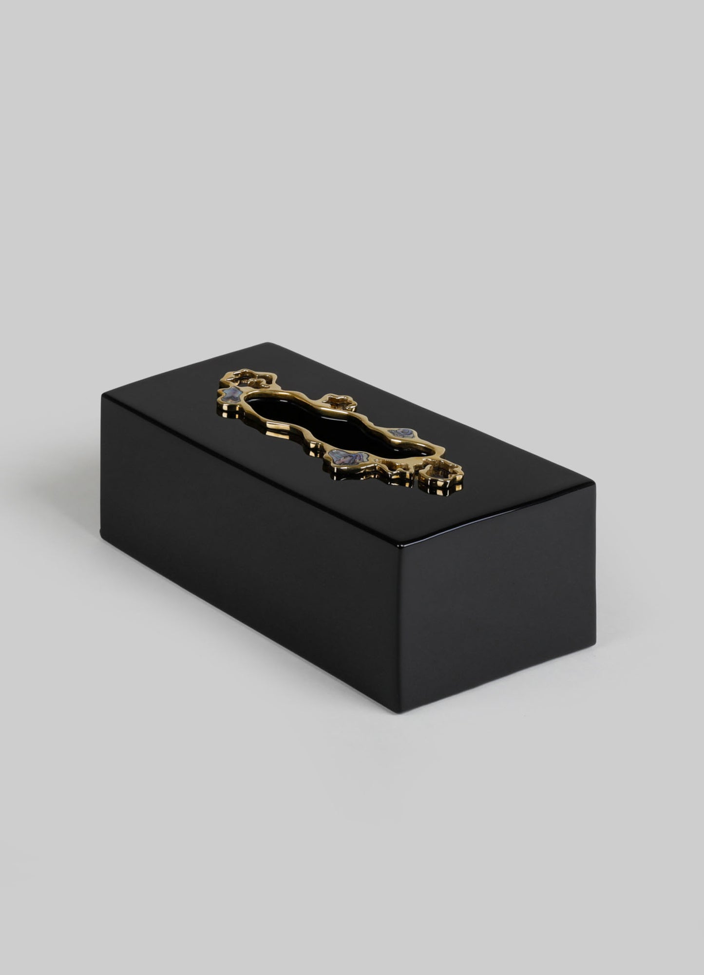 A black rectangular box with a polished finish and a decorative gold-tone metal handle on top, featuring an ornate design. The box has a sleek and minimalist style with elegant metal accents.