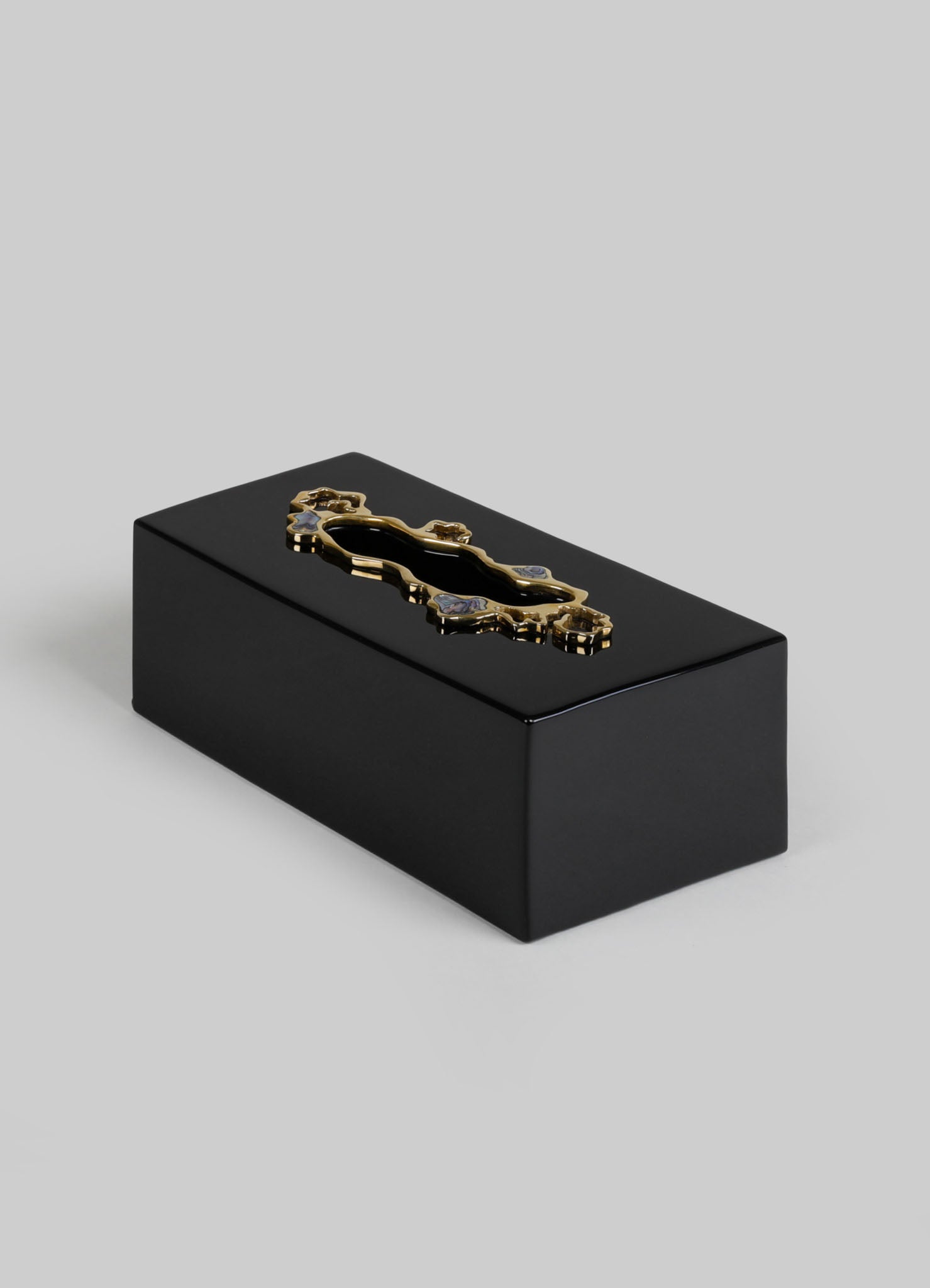 A black rectangular box with a polished finish and a decorative gold-tone metal handle on top, featuring an ornate design. The box has a sleek and minimalist style with elegant metal accents.
