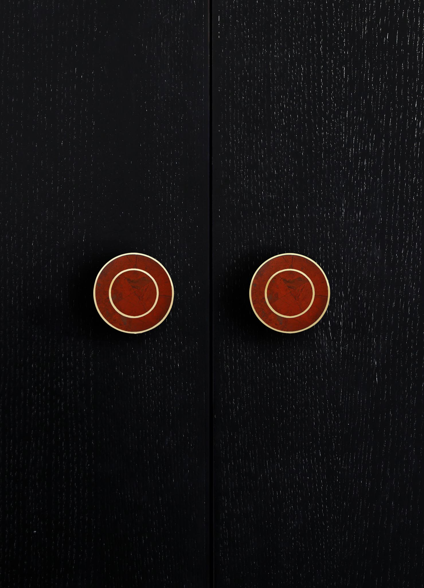 Dark wood cabinet with a textured, matte surface and two round, reddish-brown, resin-inlaid drawer pulls. The style appears contemporary with minimalist design elements.