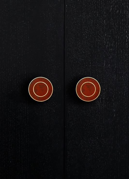 Dark wood cabinet with a textured, matte surface and two round, reddish-brown, resin-inlaid drawer pulls. The style appears contemporary with minimalist design elements.