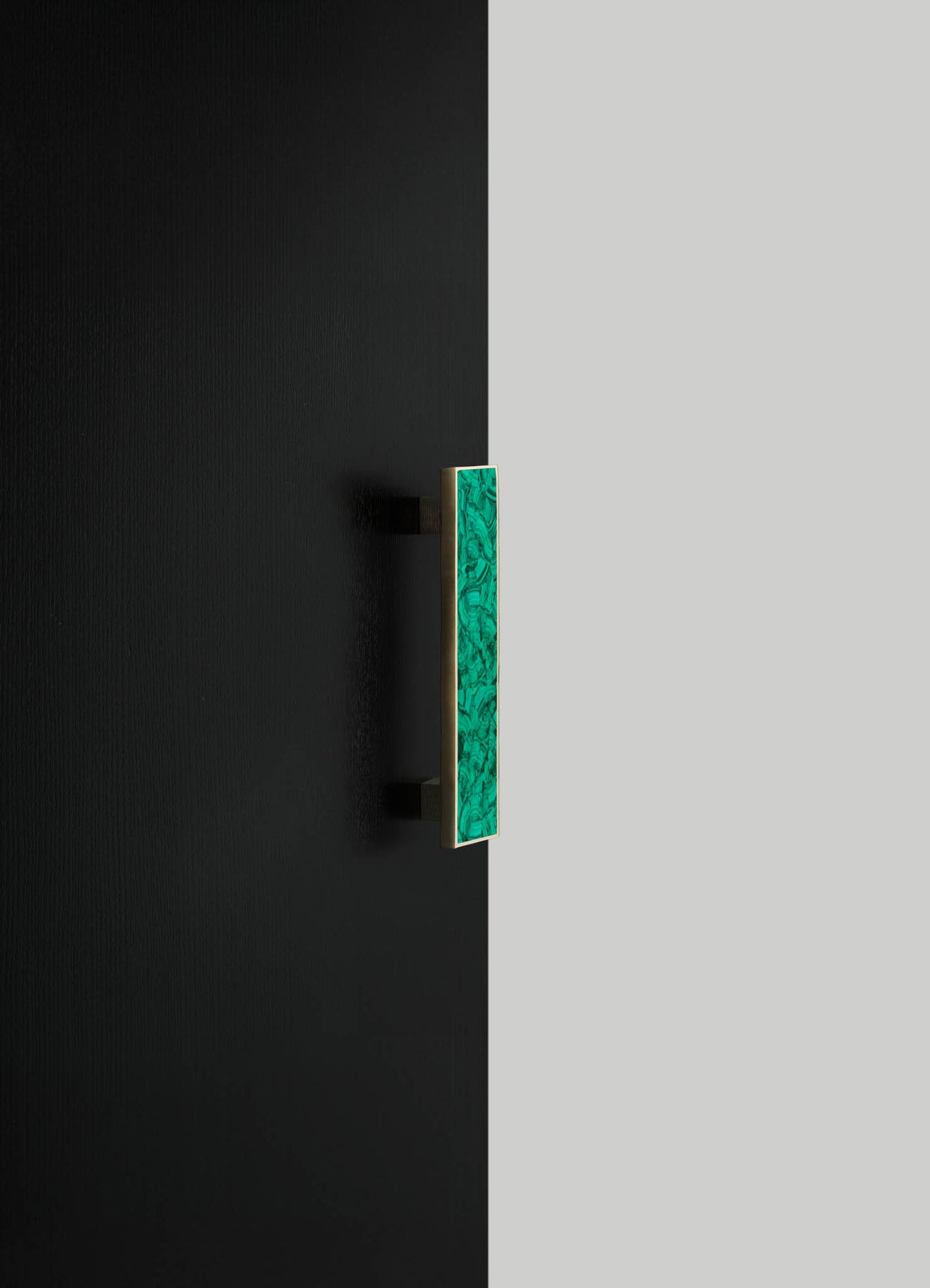 A rectangular wall sconce with a green marbled glass panel and a brass frame mounted on a black wall. The design has a contemporary style with a focus on metallic and vibrant color contrast.