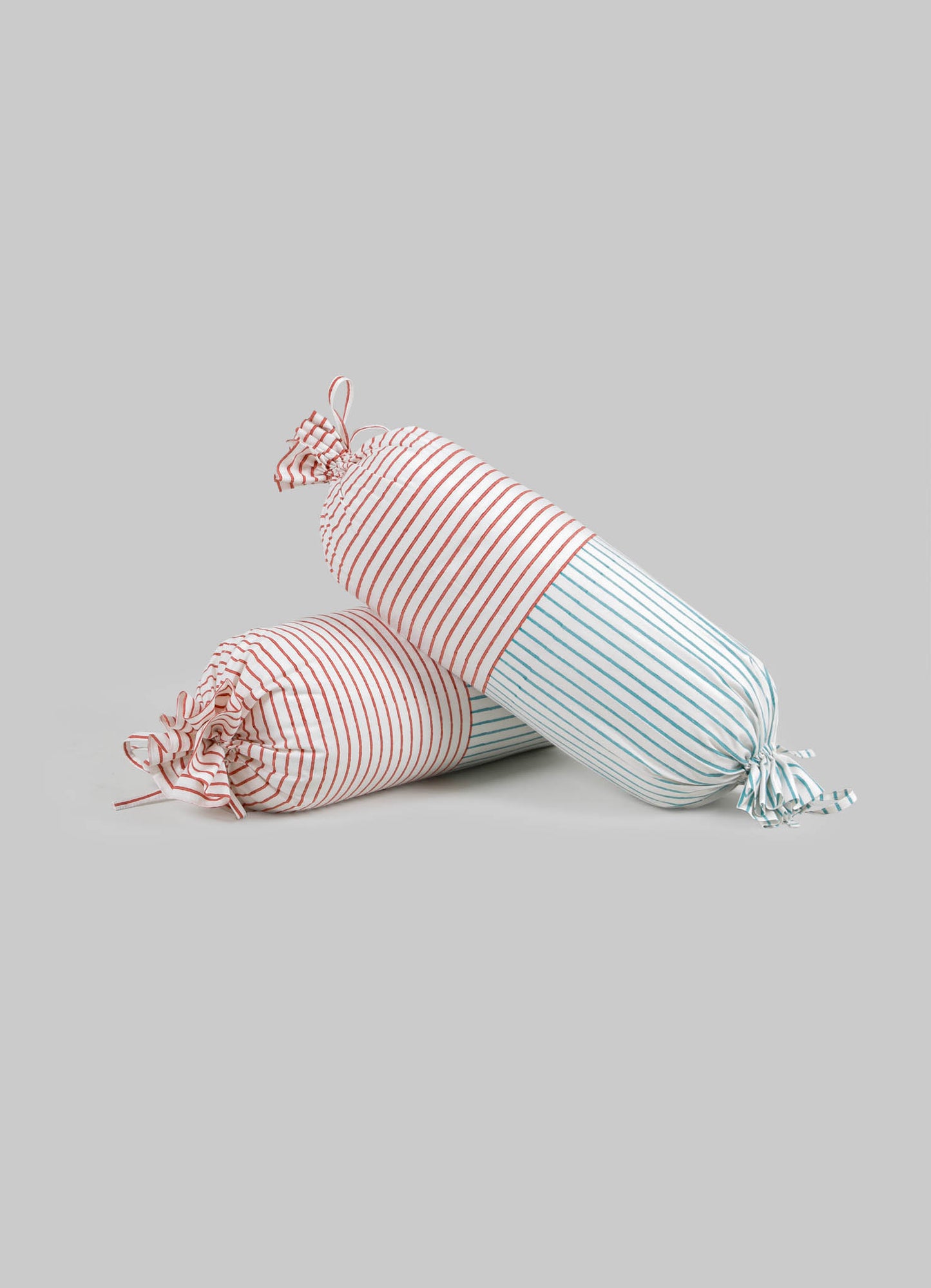 Striped fabric pencil cases with drawstring closures in red and blue and white background, made of soft textile material.