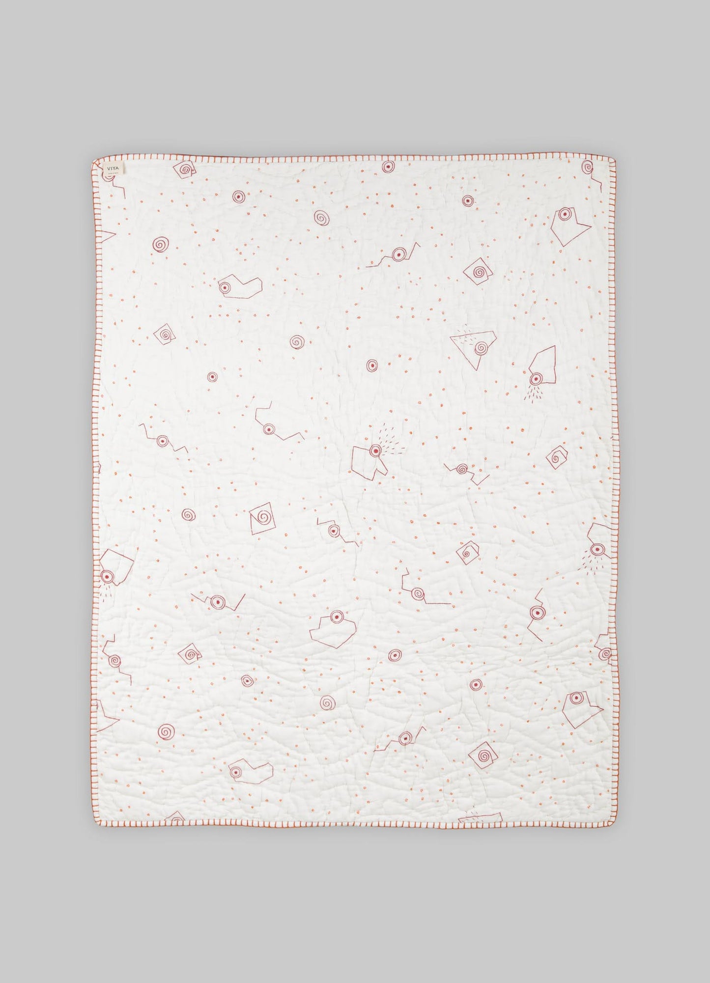 Cotton quilt with embroidered geometric motifs and a subtle color palette, edged with a contrasting border.