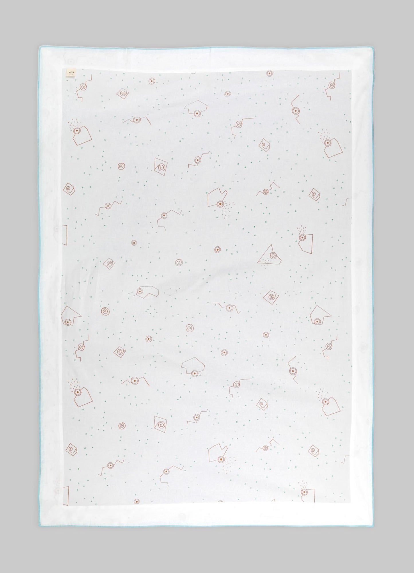 Light-colored quilt with a subtle geometric pattern featuring small dots and abstract angular motifs in pastel tones, edged with a thin contrasting border.