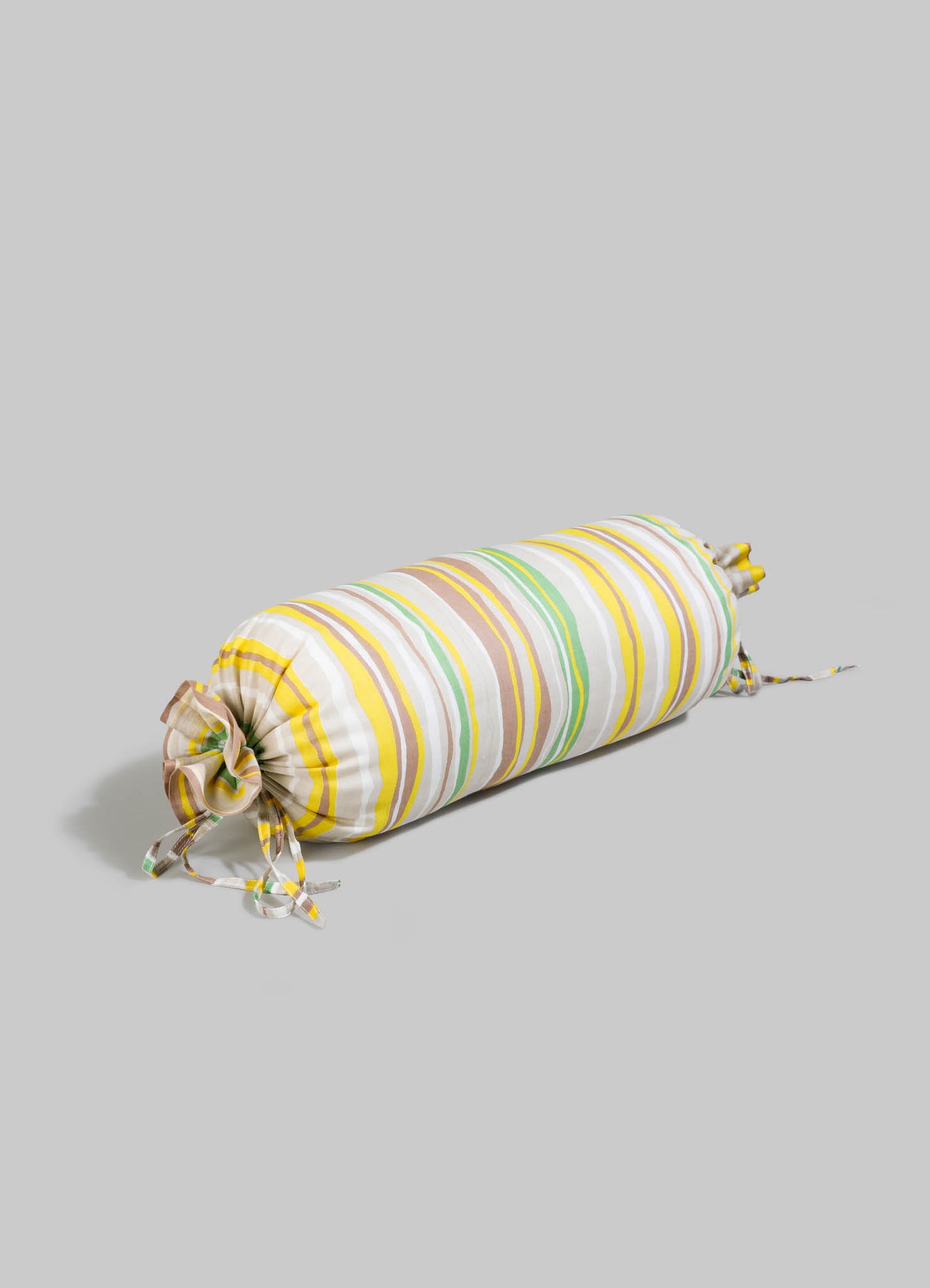 Striped fabric cushion with multicolored lines in yellow, green, white, and beige, cylindrical shape with gathered ends and ties, made of cotton or similar soft textile material.