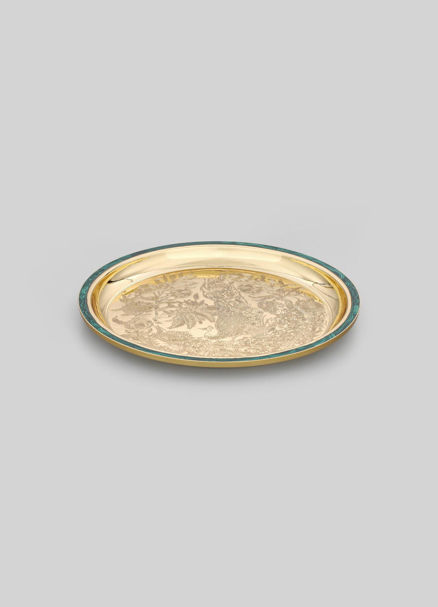 A round decorative tray with a gold-tone finish and engraved intricate motifs, bordered by a teal-colored rim.