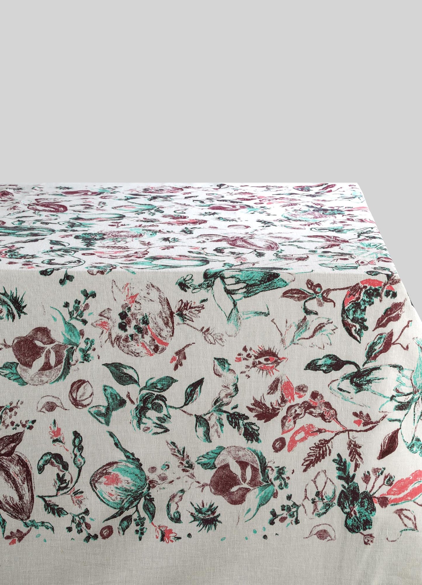 Printed fabric tablecloth with a floral motif in shades of green, brown, and pink on a cream background. The material appears to be cotton or linen, suitable for a casual or rustic dining setting.