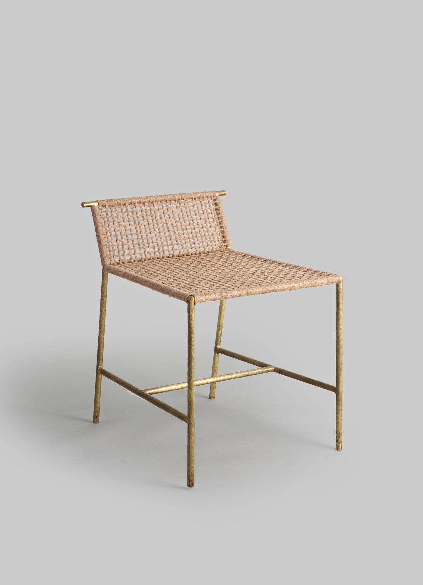 A woven rattan chair with a natural beige finish and a metal frame with a antique gold or brass look, featuring a grid-patterned backrest and seat. The design combines handcrafted rattan with a rustic metal structure, presenting a contemporary rustic style.