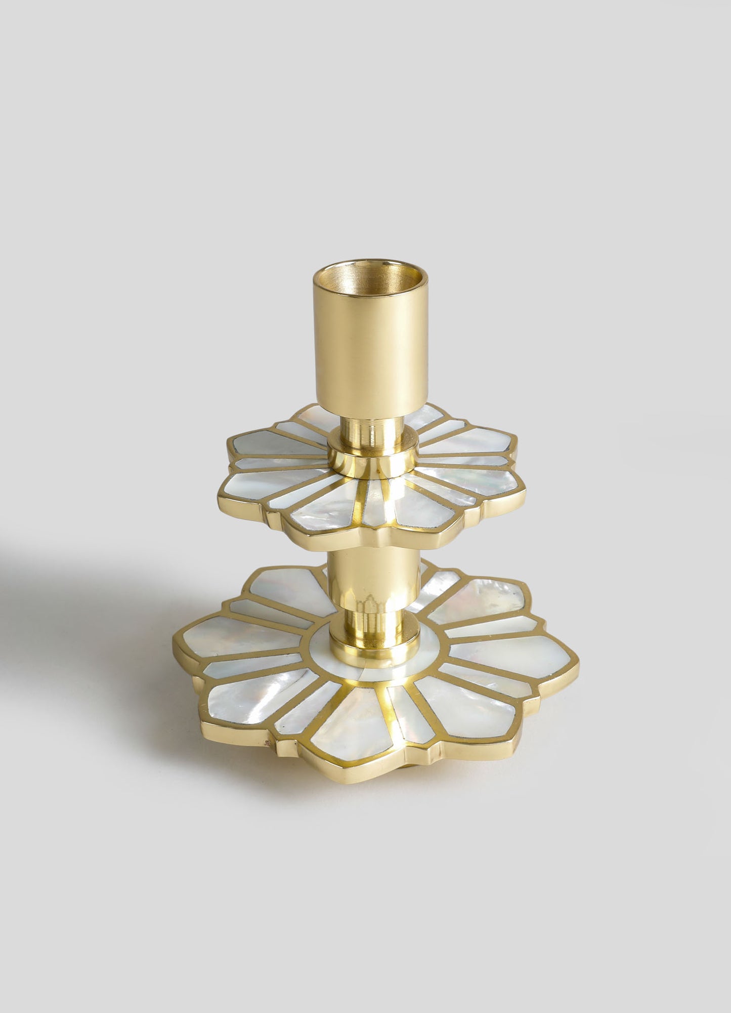 A decorative candle holder with a gold finish and floral motif, featuring two tiered, scalloped edges with embedded iridescent inlay.