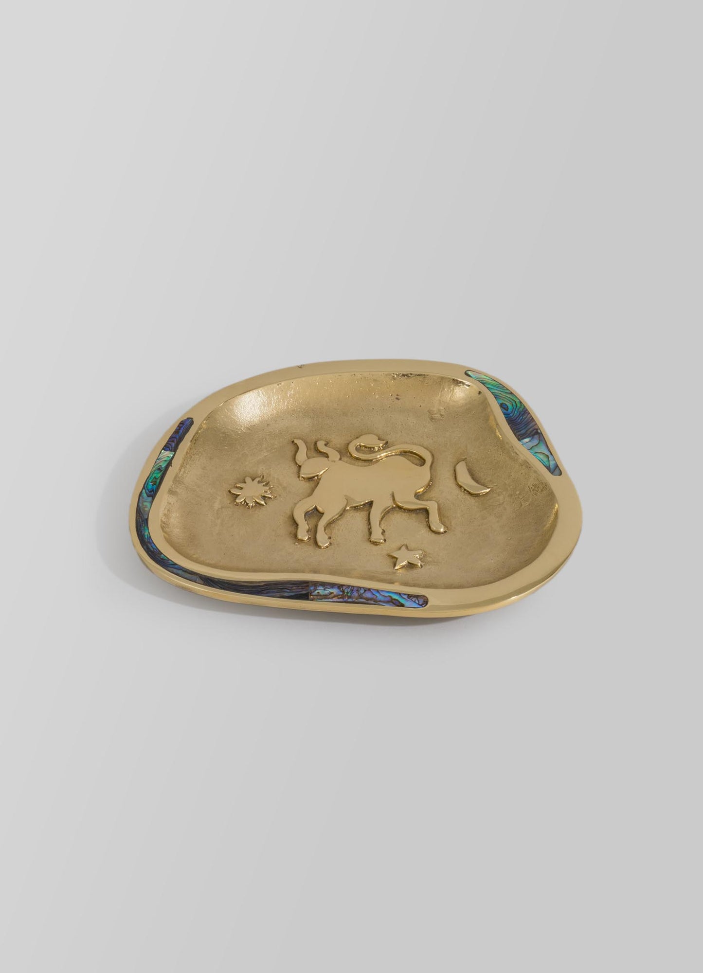 A decorative metal dish with a gold finish, featuring a raised lion motif and bordered by inlaid abalone shell accents in shades of blue and green.