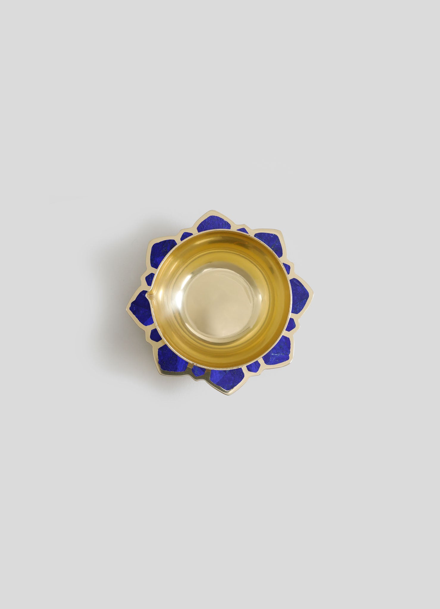 A decorative bowl with a gold interior and a scalloped outer edge featuring blue enamel inlay, crafted in a mosaic style.