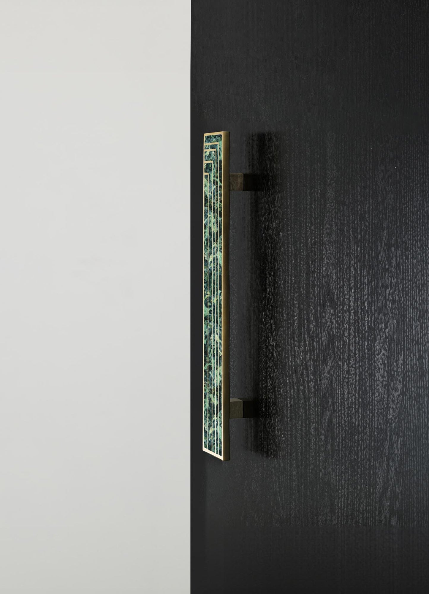 A decorative wall-mounted piece with a rectangular brass frame featuring a geometric pattern in green and blue tones, mounted on a black textured wall.