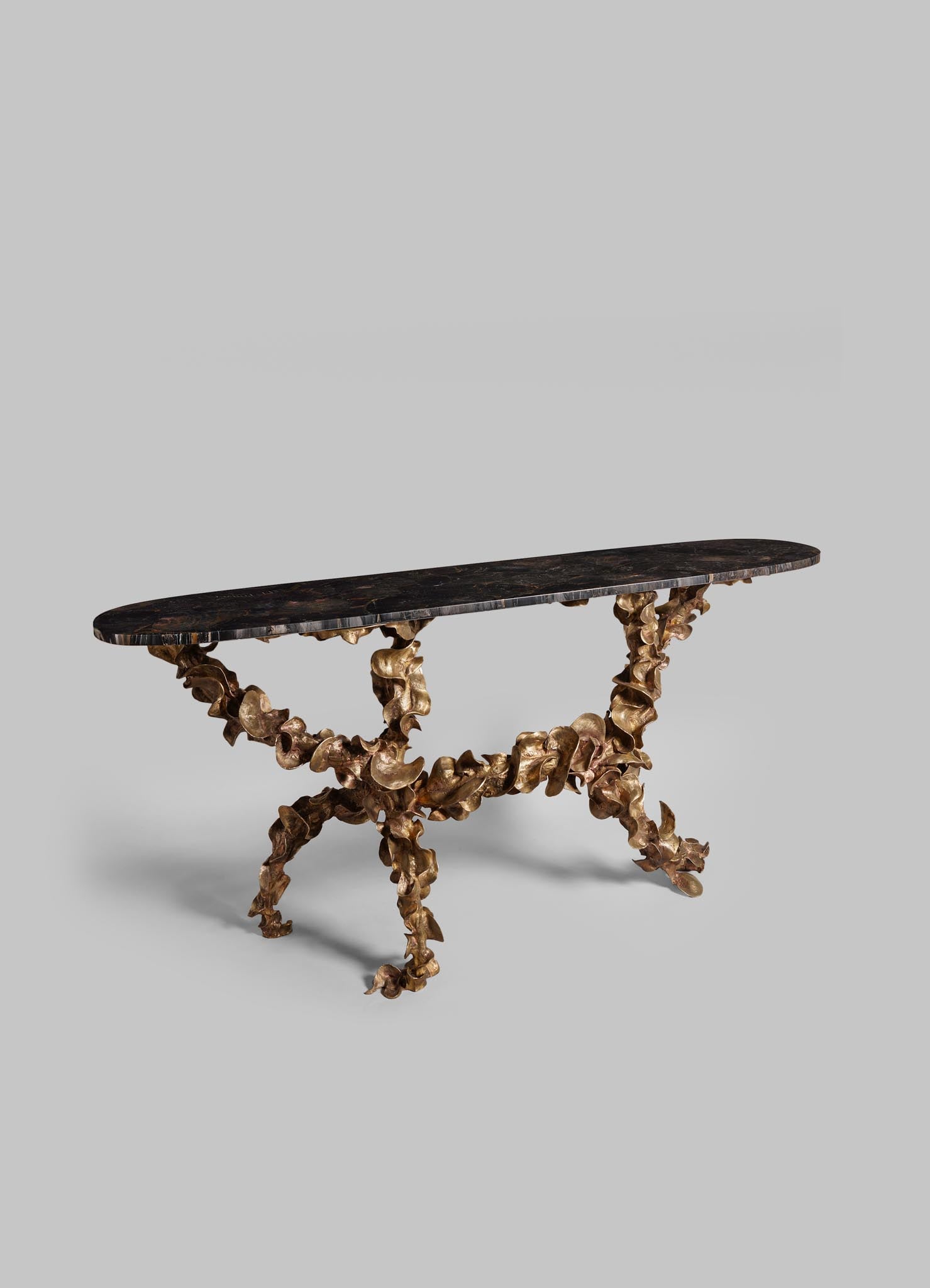 A console table with a dark, polished wooden top and a sculptural base made of intertwined metallic gold elements, featuring an organic, botanical-inspired design.