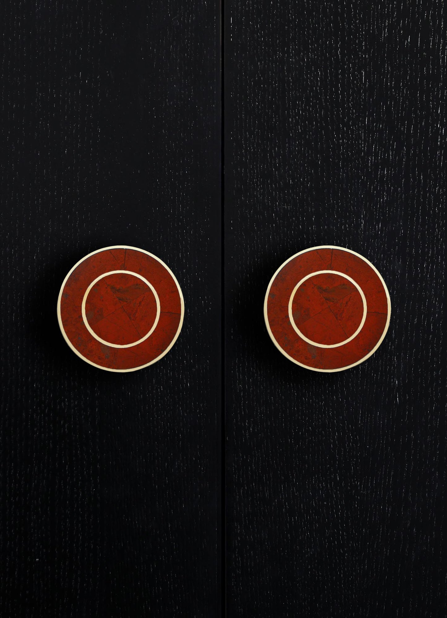 Black wooden surface with two round, red-brown ceramic drawer knobs accented by white trim, creating a modern minimalist piece with contrasting tones and smooth finish.