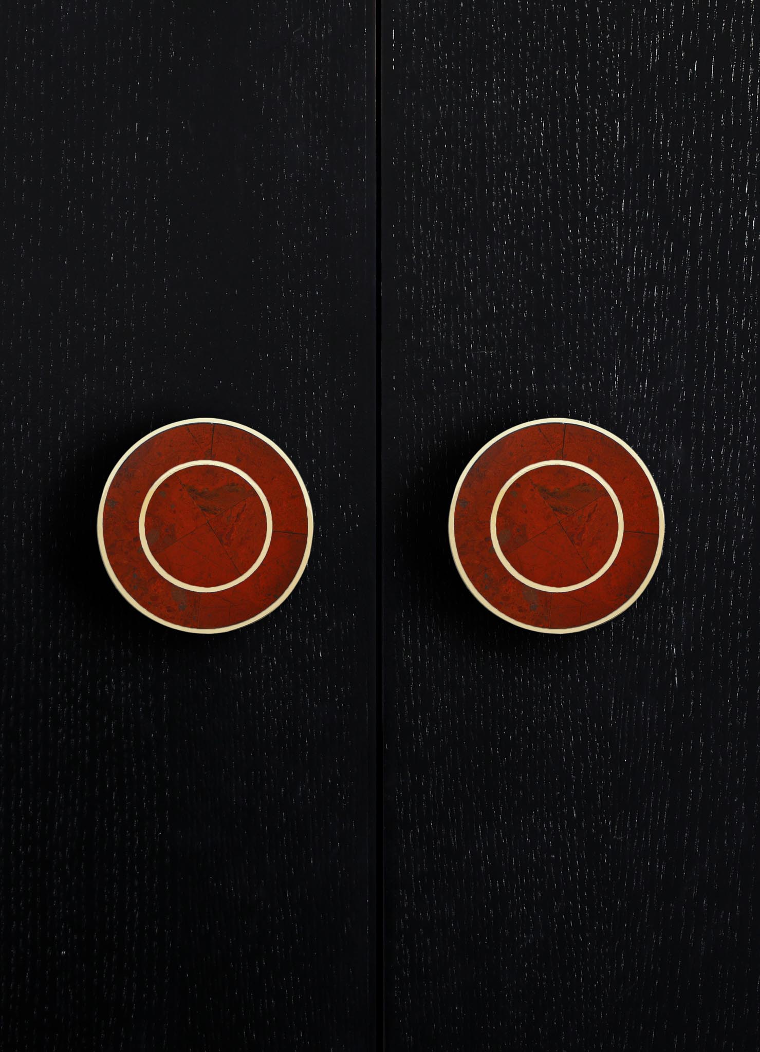 Black wooden surface with two round, red-brown ceramic drawer knobs accented by white trim, creating a modern minimalist piece with contrasting tones and smooth finish.