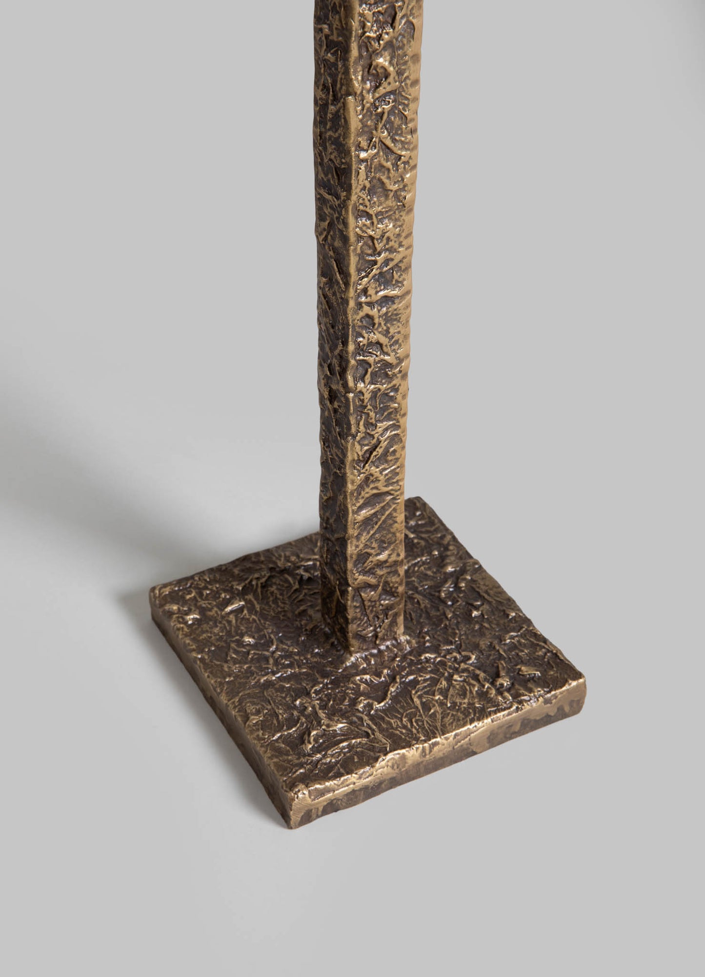 A metal table lamp base with a textured, hammered finish in antique brass tone, featuring a square-shaped base and a tall, narrow body. The design is contemporary with a handcrafted aesthetic.