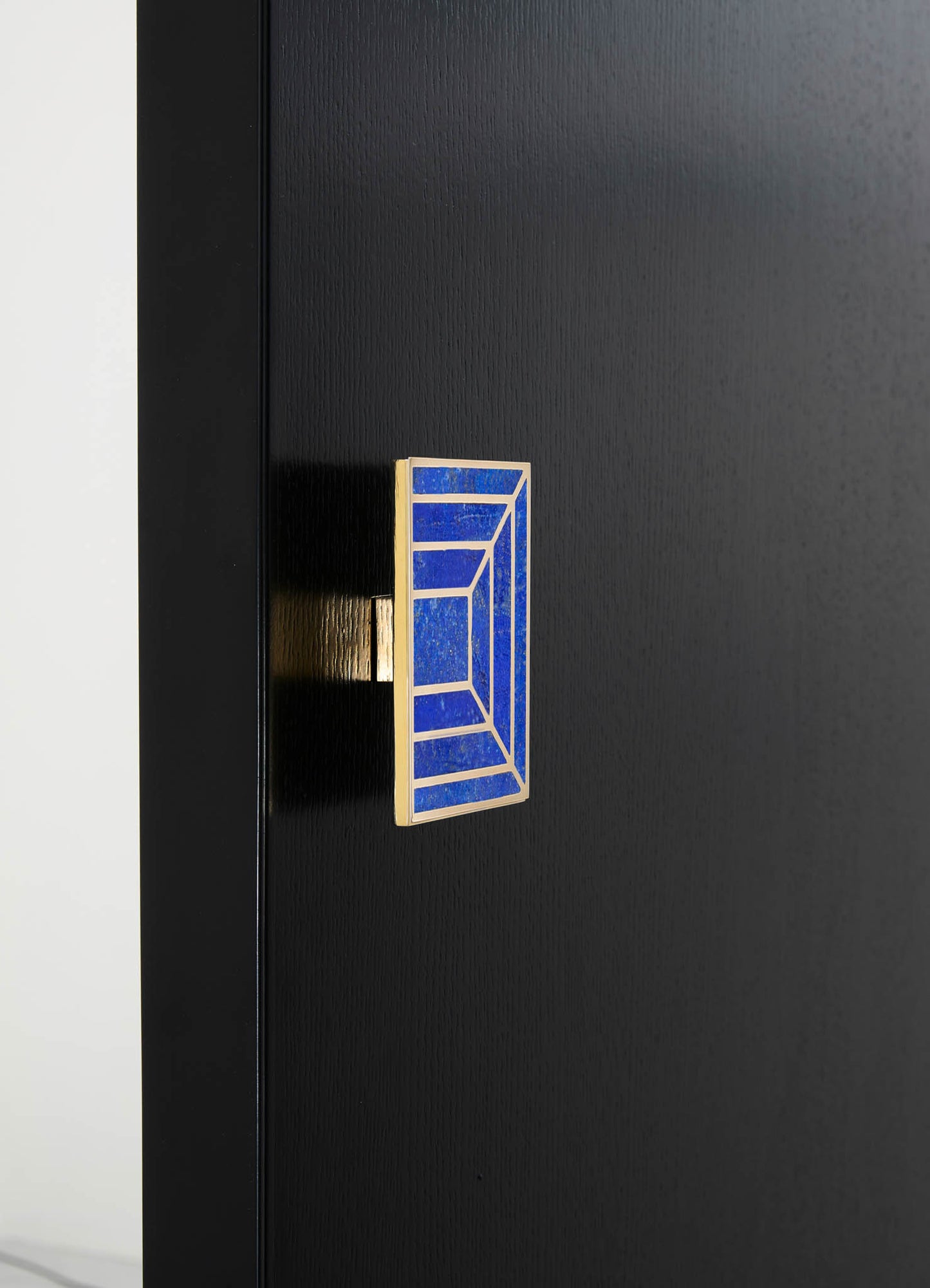 A decorative wall hook with a rectangular shape, featuring blue mosaic tiles bordered by a gold-tone frame, mounted on a black wall surface.
