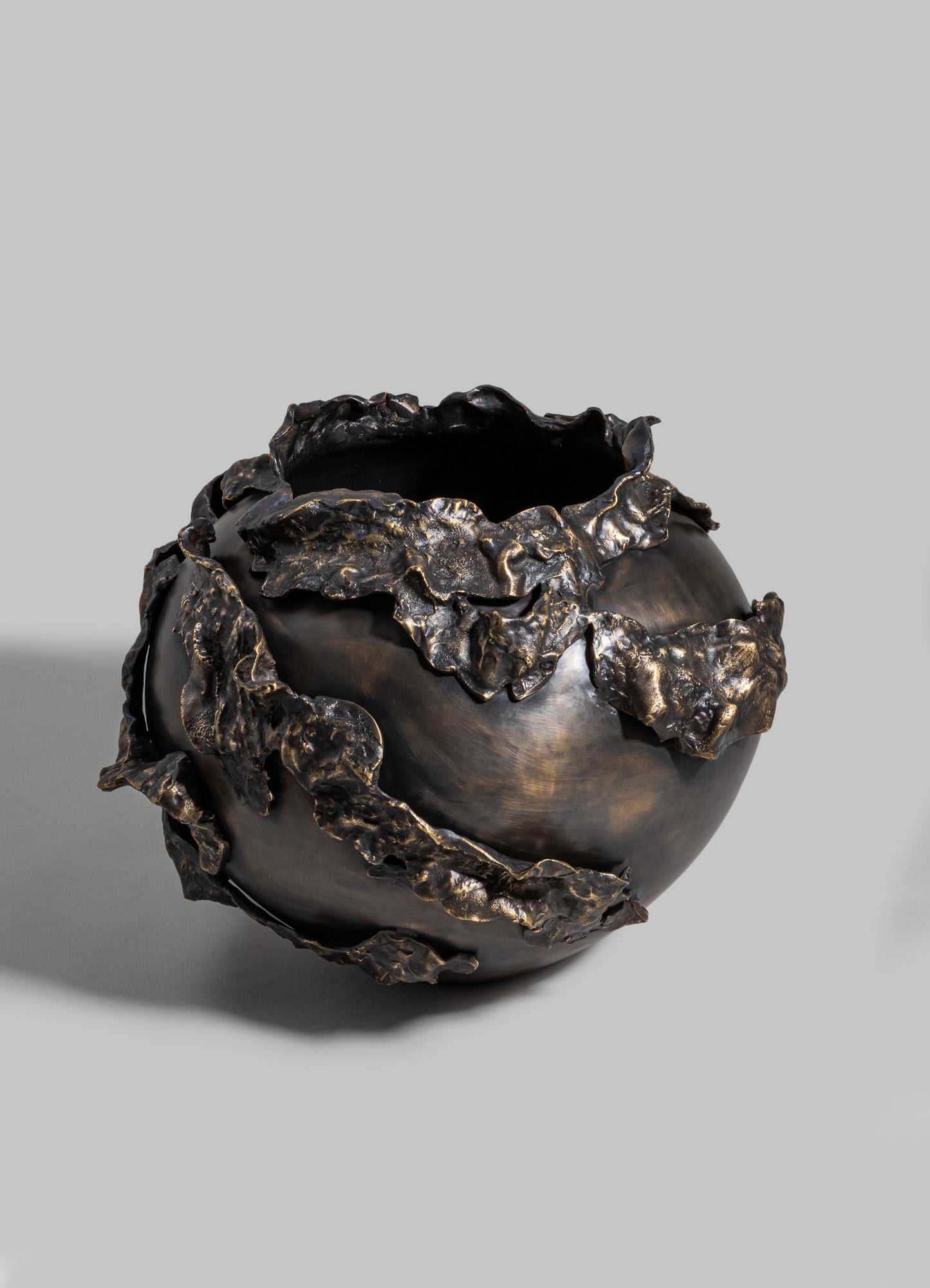 Bronze decorative vase with a glossy, dark finish and textured, ruffled edges resembling leaves, set against a neutral gray background.