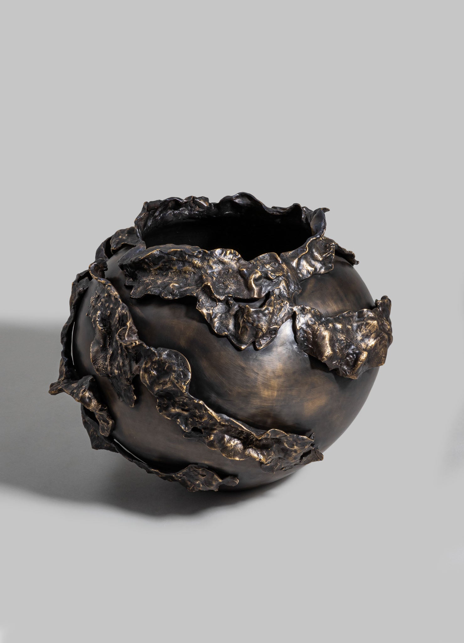 Bronze decorative vase with a glossy, dark finish and textured, ruffled edges resembling leaves, set against a neutral gray background.