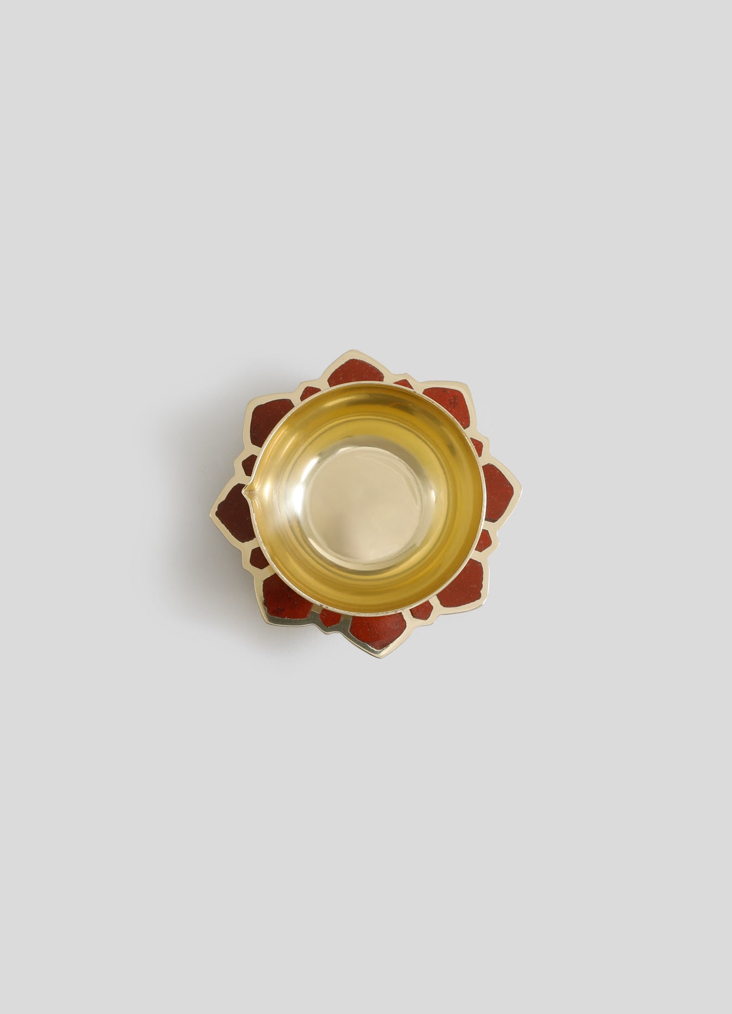 A decorative bowl with a metallic gold interior and a scalloped outer edge featuring red and beige enamel inlay, set against a plain light background.