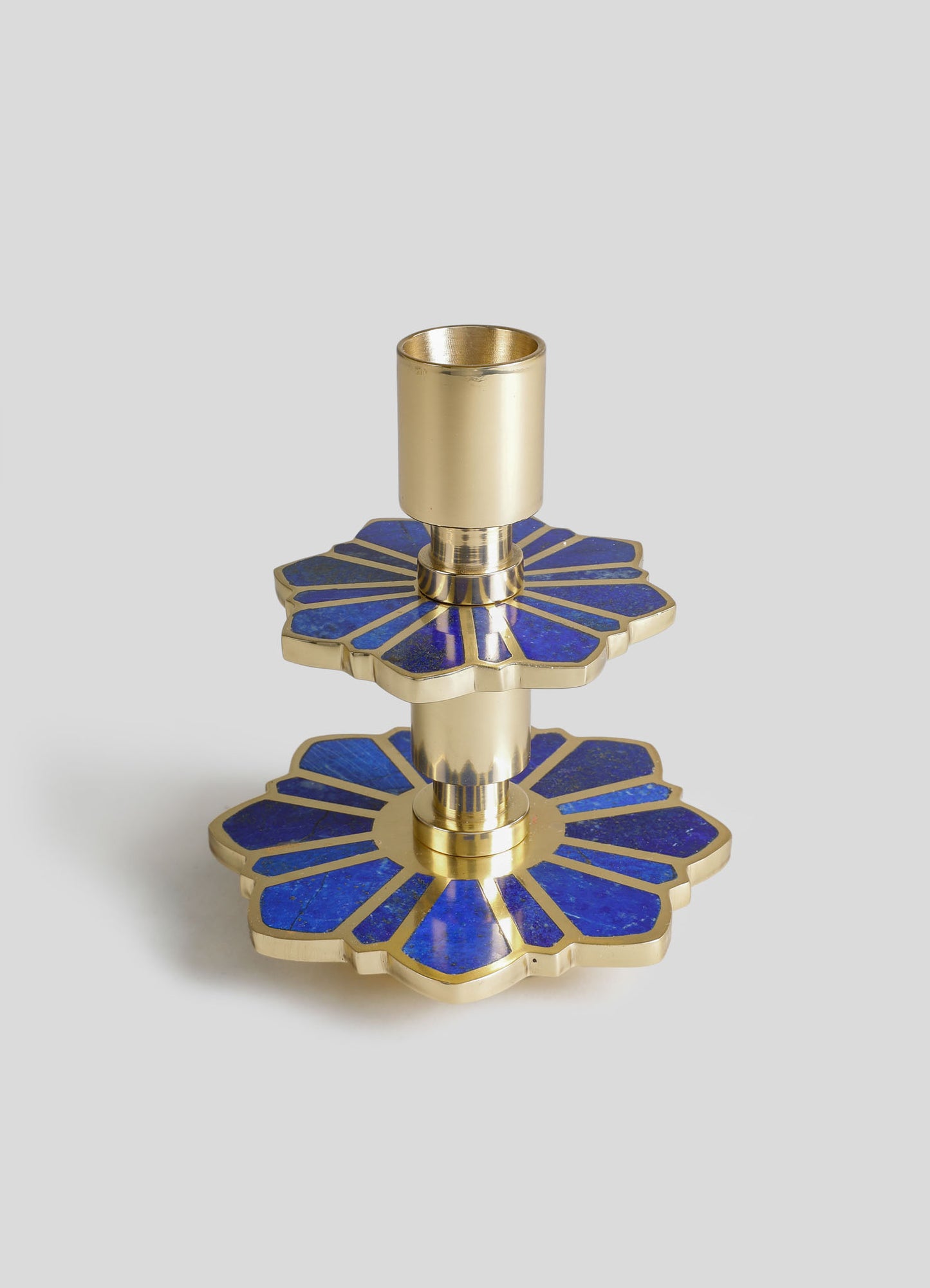 Brass candle holder with a blue and gold floral motif design, featuring a tiered flower-shaped base with enamel detailing and a cylindrical holder for a candle.