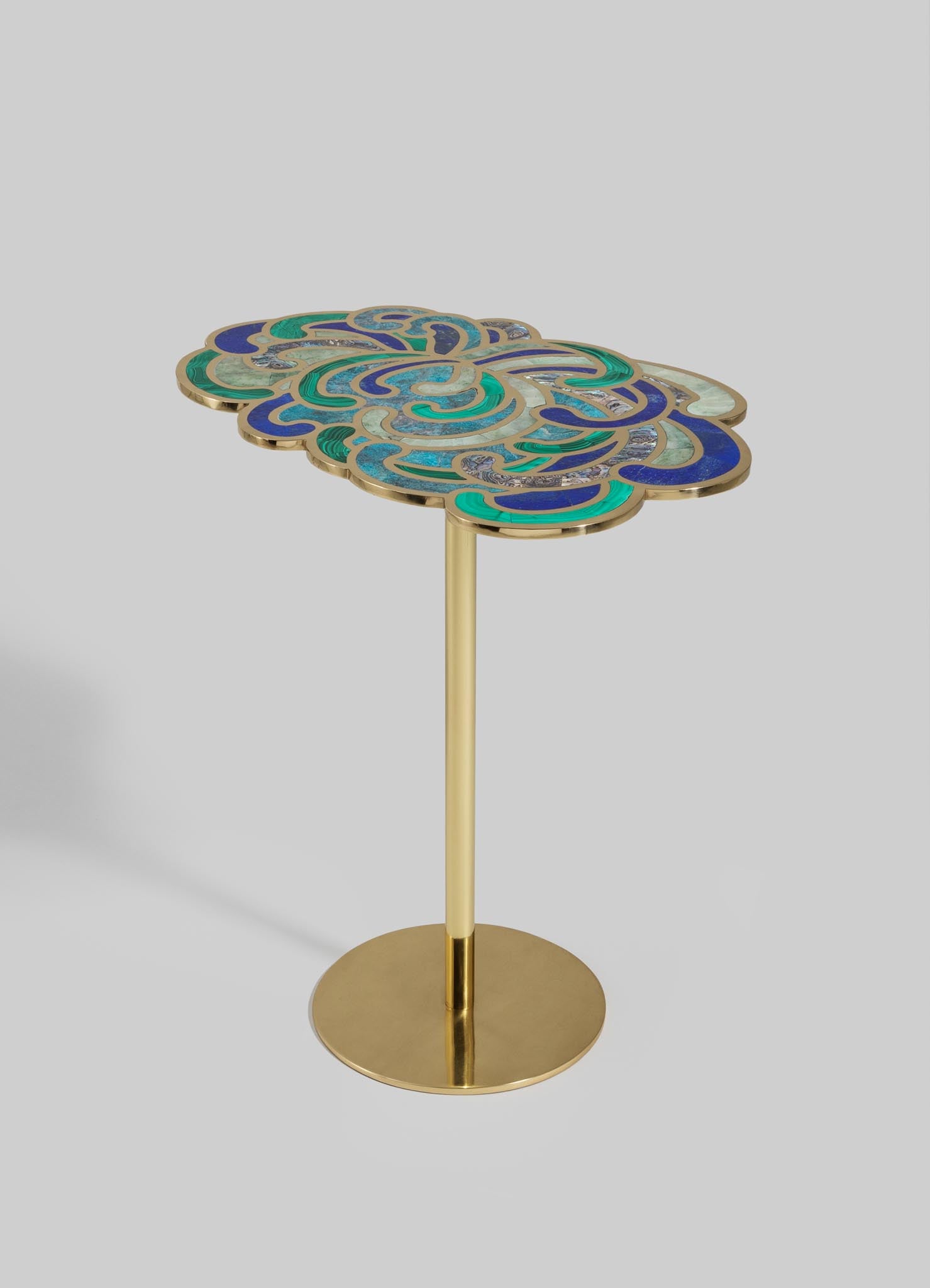 A decorative side table with a brass base and a mosaic-patterned tabletop featuring shades of blue, green, and beige in an abstract swirling design.