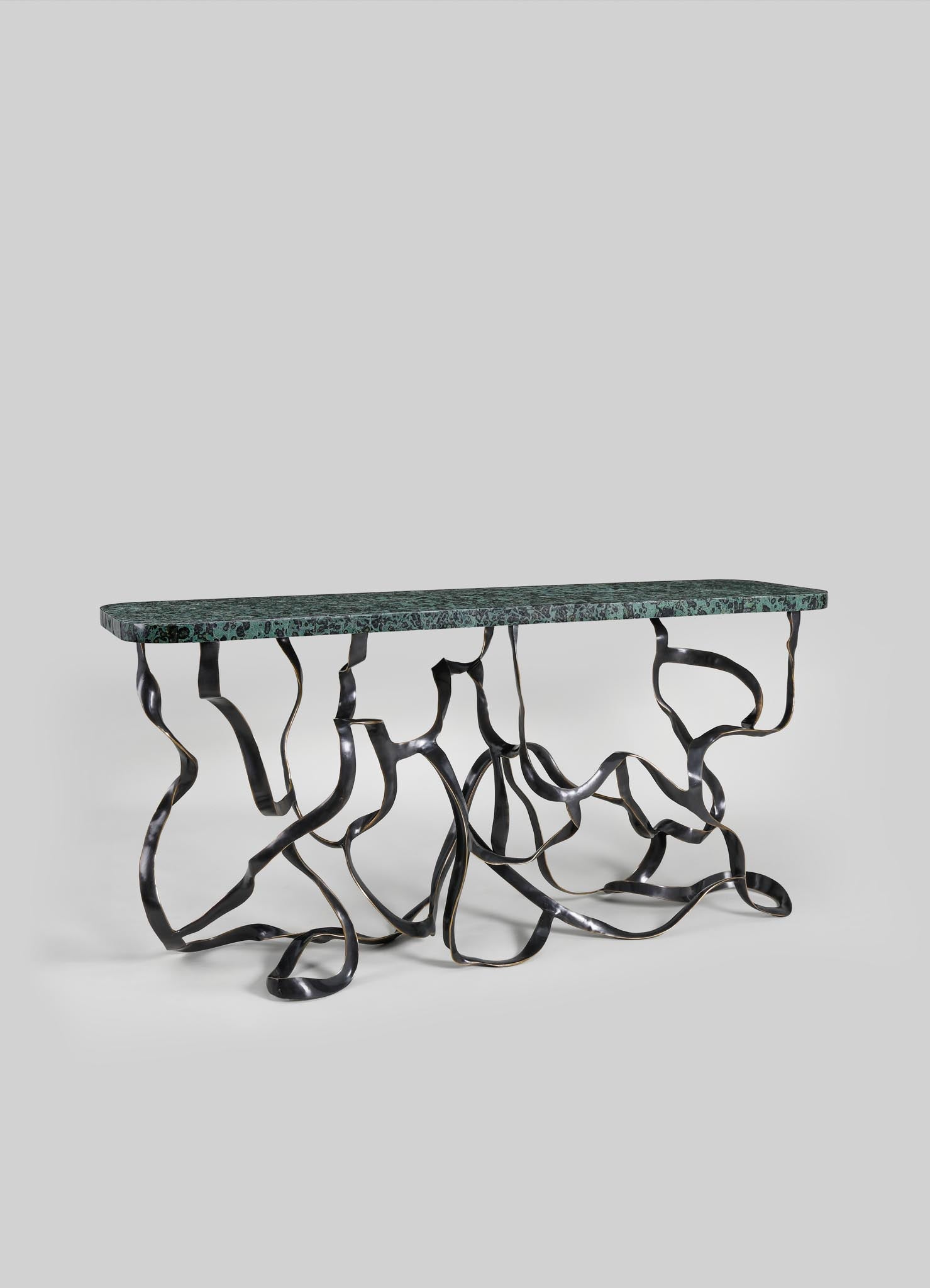 A decorative table with a dark green marble top and a sculptural metal base featuring twisted, organic-shaped legs in black and metallic finish.