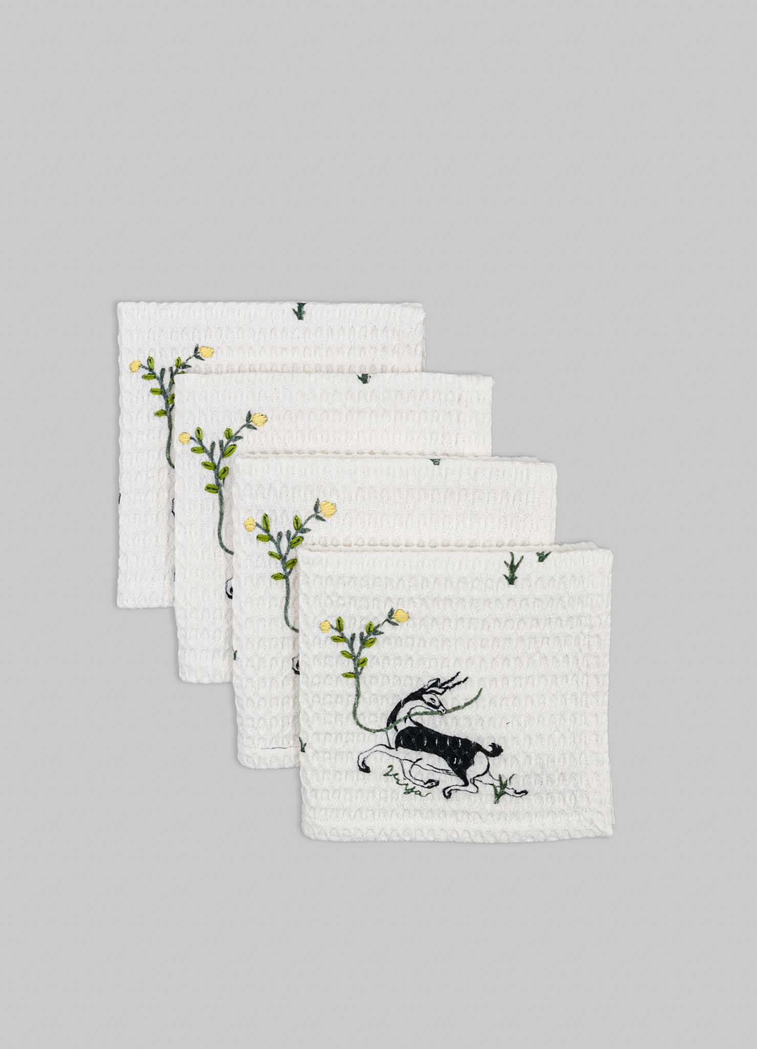 Set of four white waffle-weave dishcloths with embroidered black and yellow bee motifs and green leaf stems, featuring a textured surface and delicate stitching.