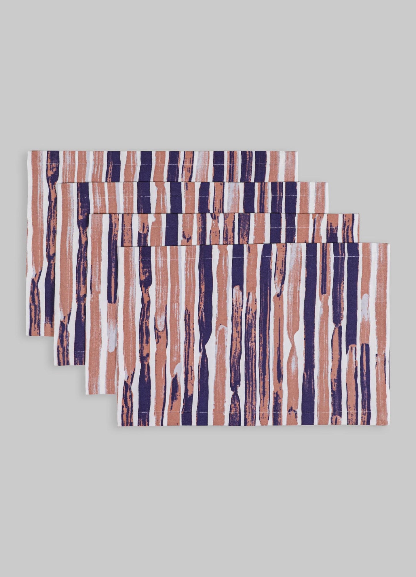 Set of four rectangular placemats made from woven fabric featuring a striped pattern in shades of navy blue, light pink, and white, with a slightly textured surface on a plain background.