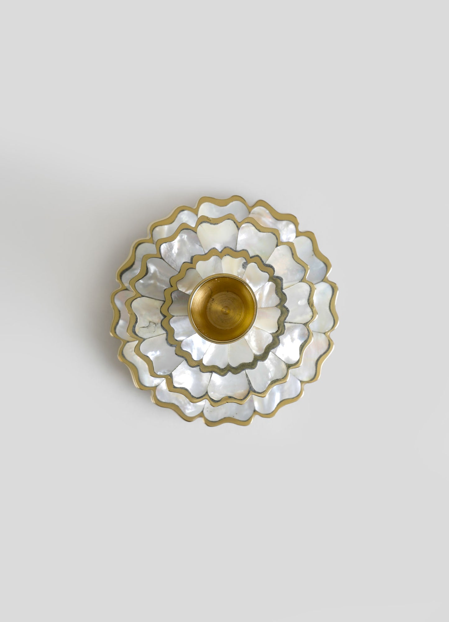 A decorative ceiling light fixture featuring layered scalloped shells with a mother-of-pearl finish and gold accents, arranged in a floral pattern with a central brass socket.