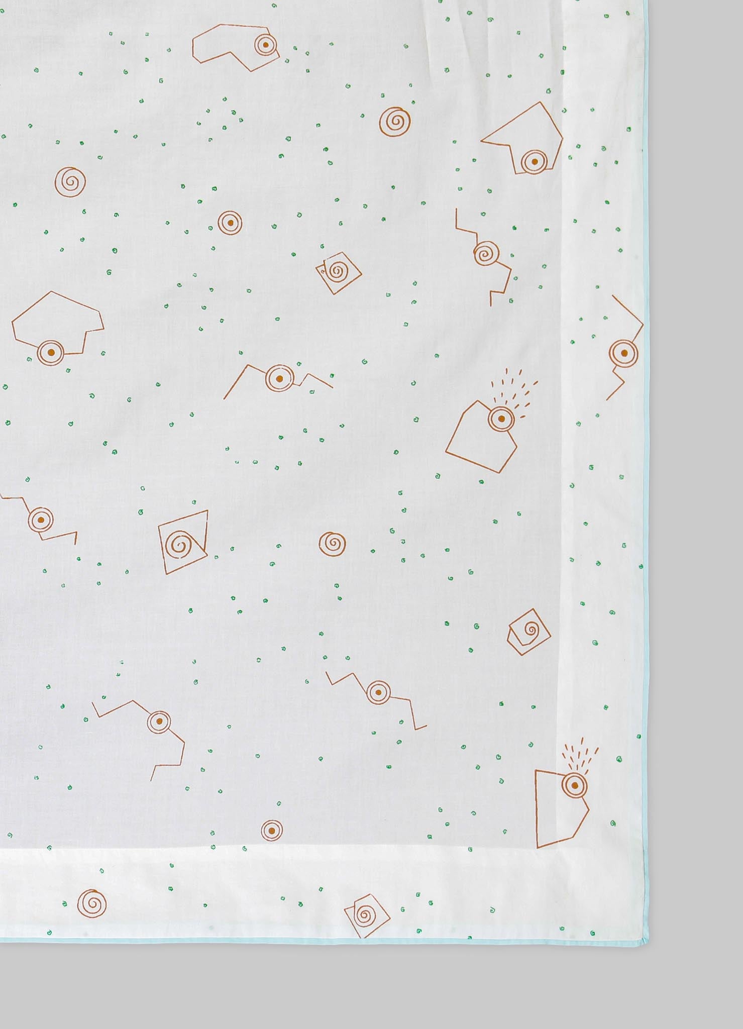 A white tablecloth with a minimalist geometric pattern featuring orange spiral and square motifs, accented by small green dots scattered across the fabric. The edges of the tablecloth are finished with a light blue trim.
