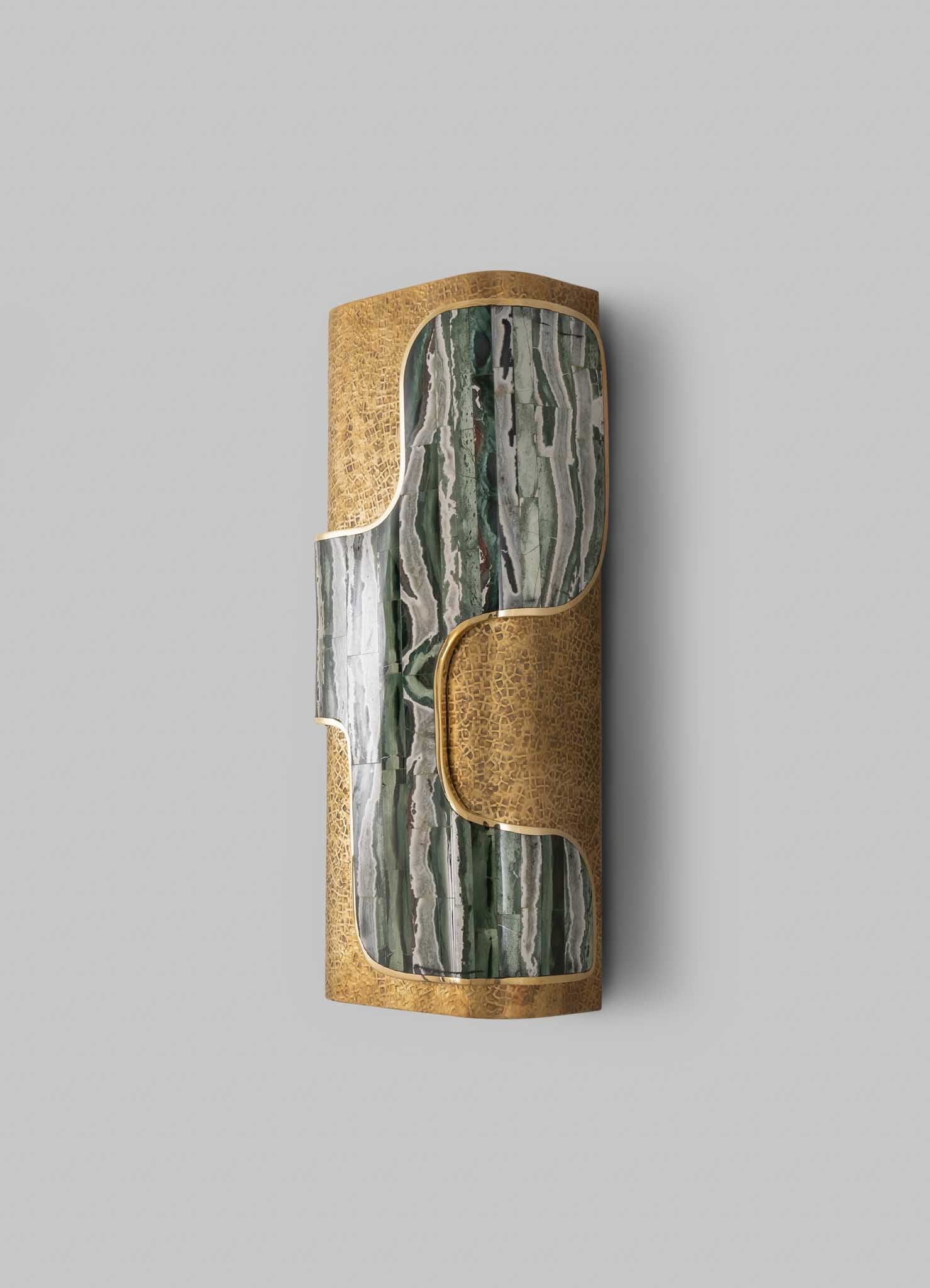 A decorative wall-mounted sculpture with a combination of polished green and gray marble and textured brass detailing, featuring organic curved shapes and a cylindrical form.