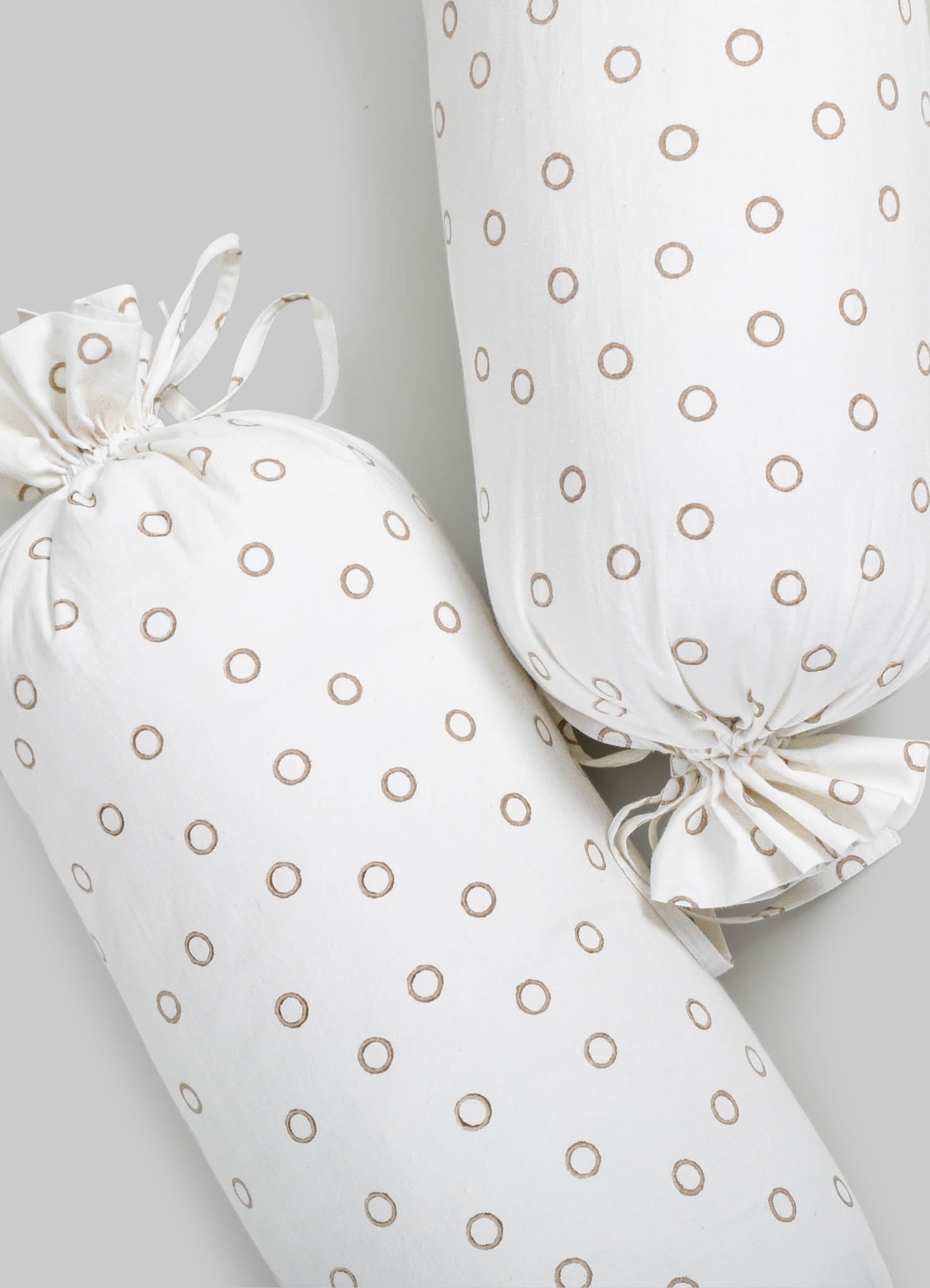 Cotton fabric cushion covers with a beige circle pattern, featuring gathered ties on the ends for securing. The fabric has a soft, matte finish with a neutral color palette.