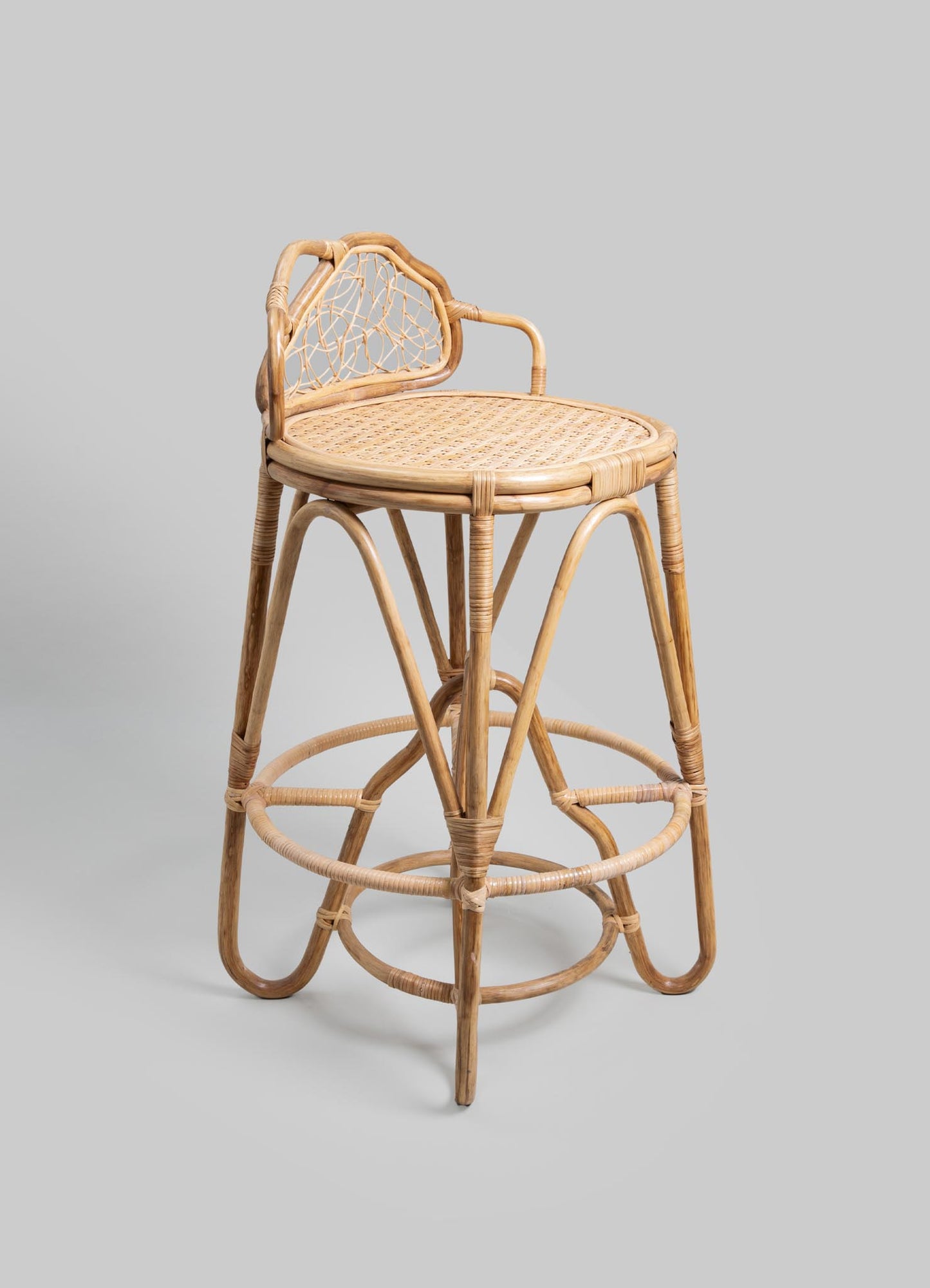 A rattan barstool with a round woven seat, curved armrest, and a decorative backrest featuring an open geometric pattern, showcasing natural wood tones and handcrafted detailing.