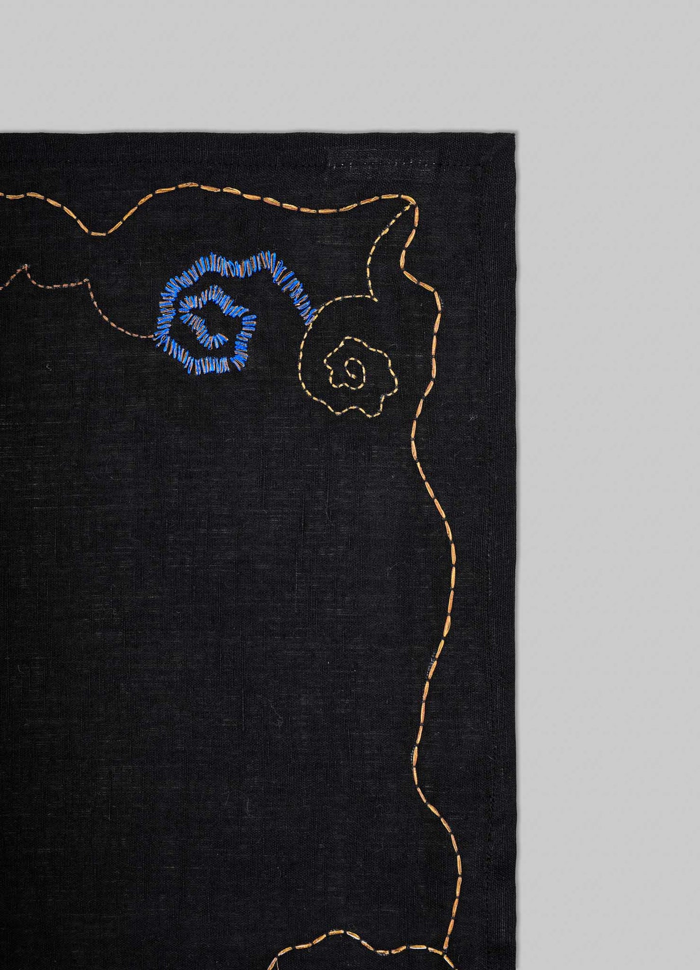 Black fabric with embroidered blue floral design on a gray background viya placemats