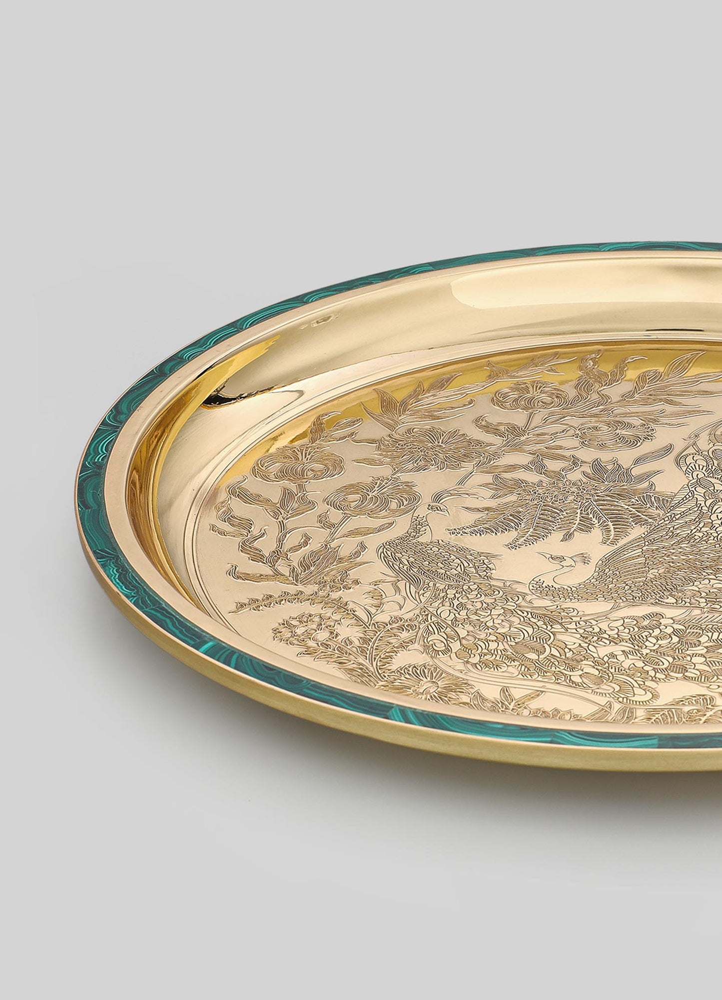 A decorative metal tray featuring intricate engraved motifs of birds and floral patterns, with a polished gold finish and a contrasting teal-colored border.