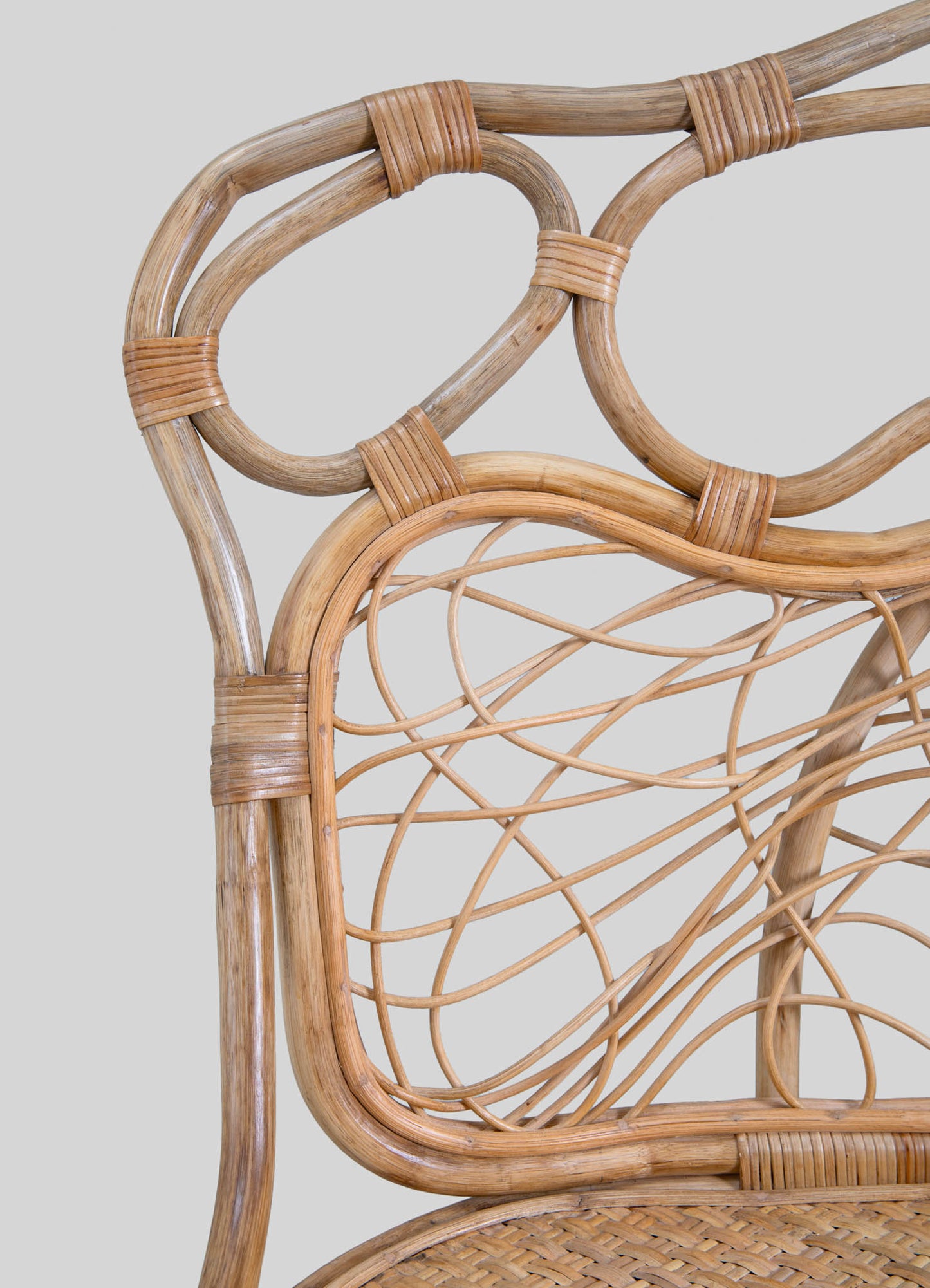 Wicker chair with a natural rattan frame, featuring intricate woven patterns and rounded edges. The light beige tones highlight a handcrafted, rustic style suitable for casual or bohemian interior decor.